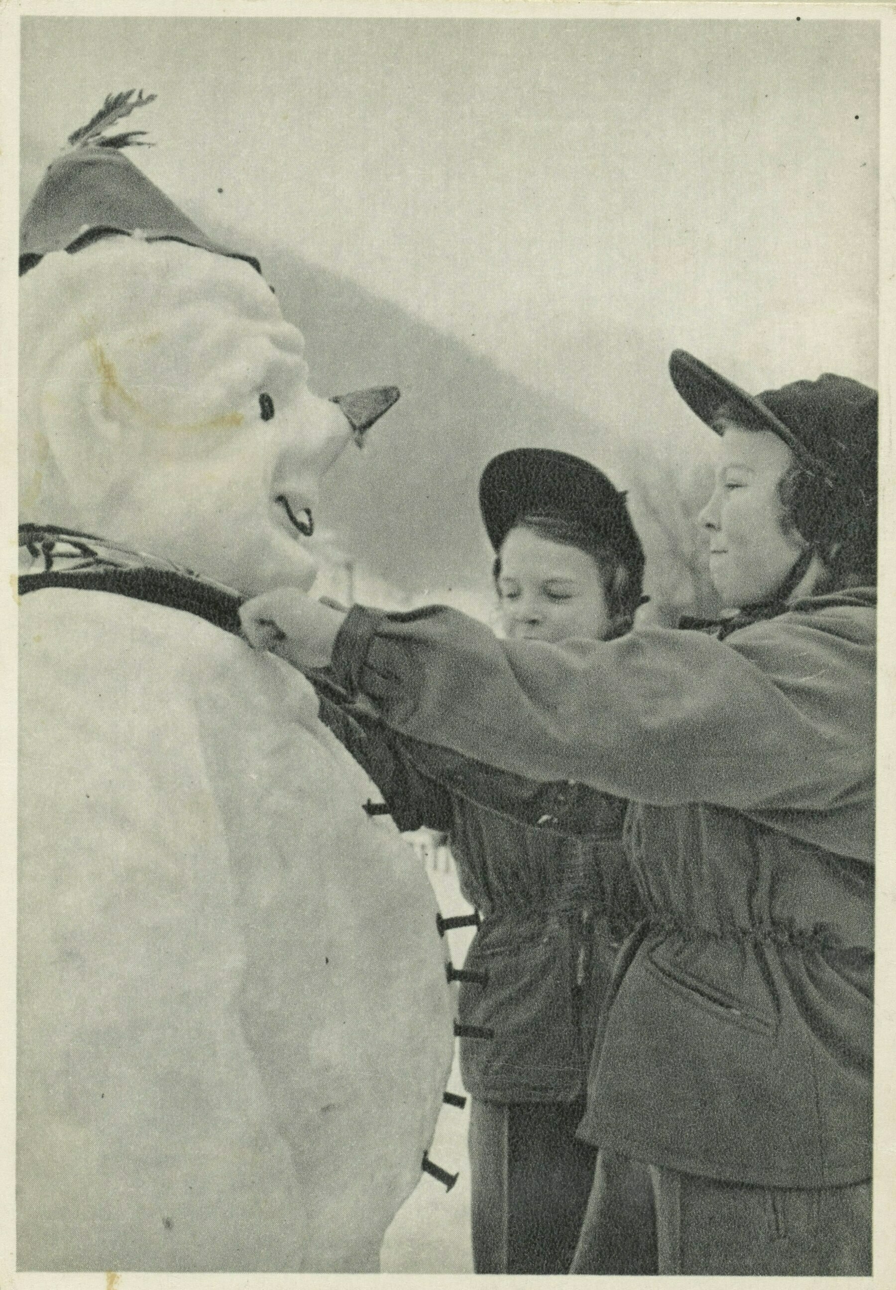 Two children from the 1950s with the snowman they built.