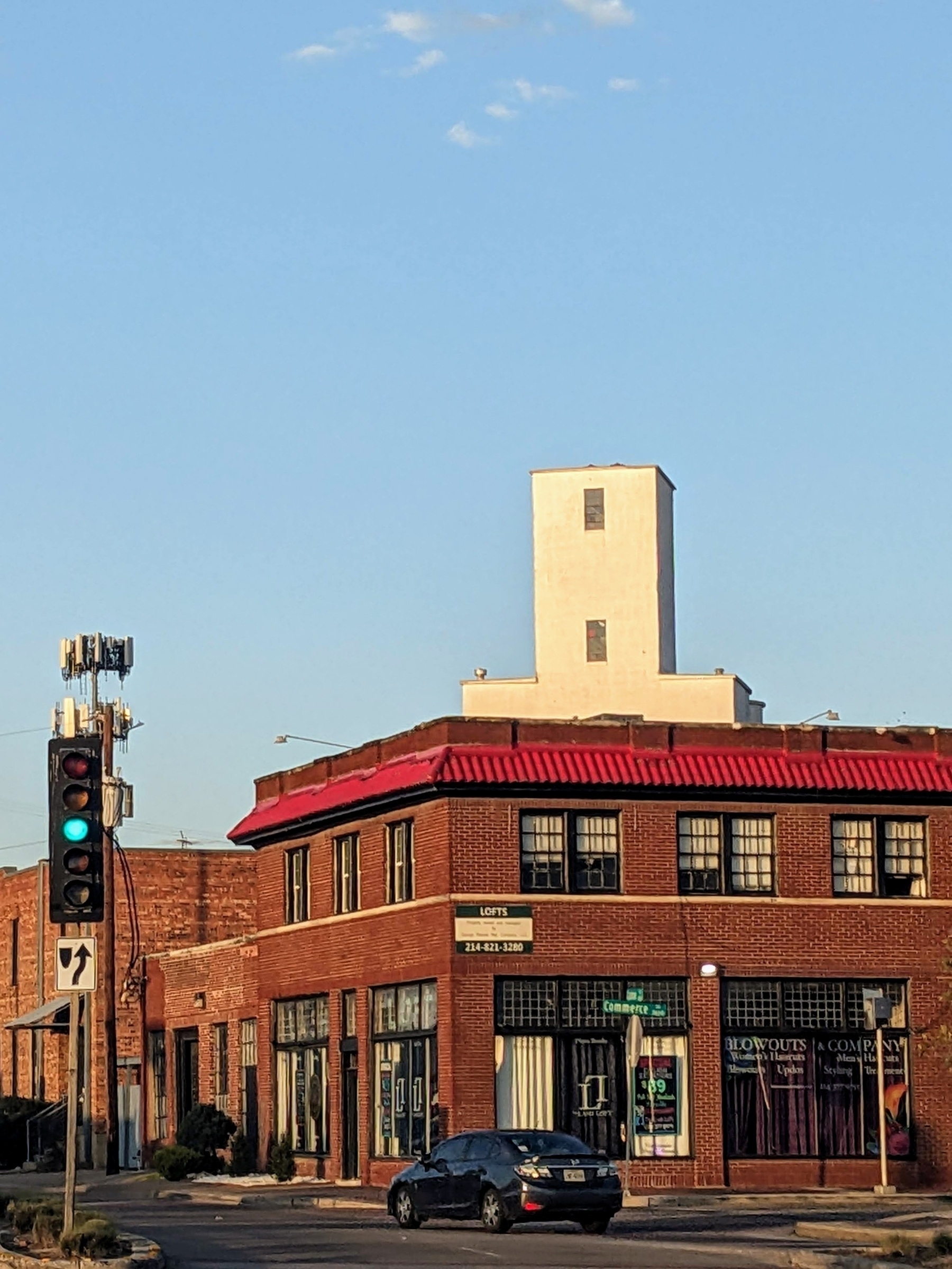 A golden hour photo of brick and tile buildings with a white silo structure behind them in Dallas' Deep Ellum neighborhood.