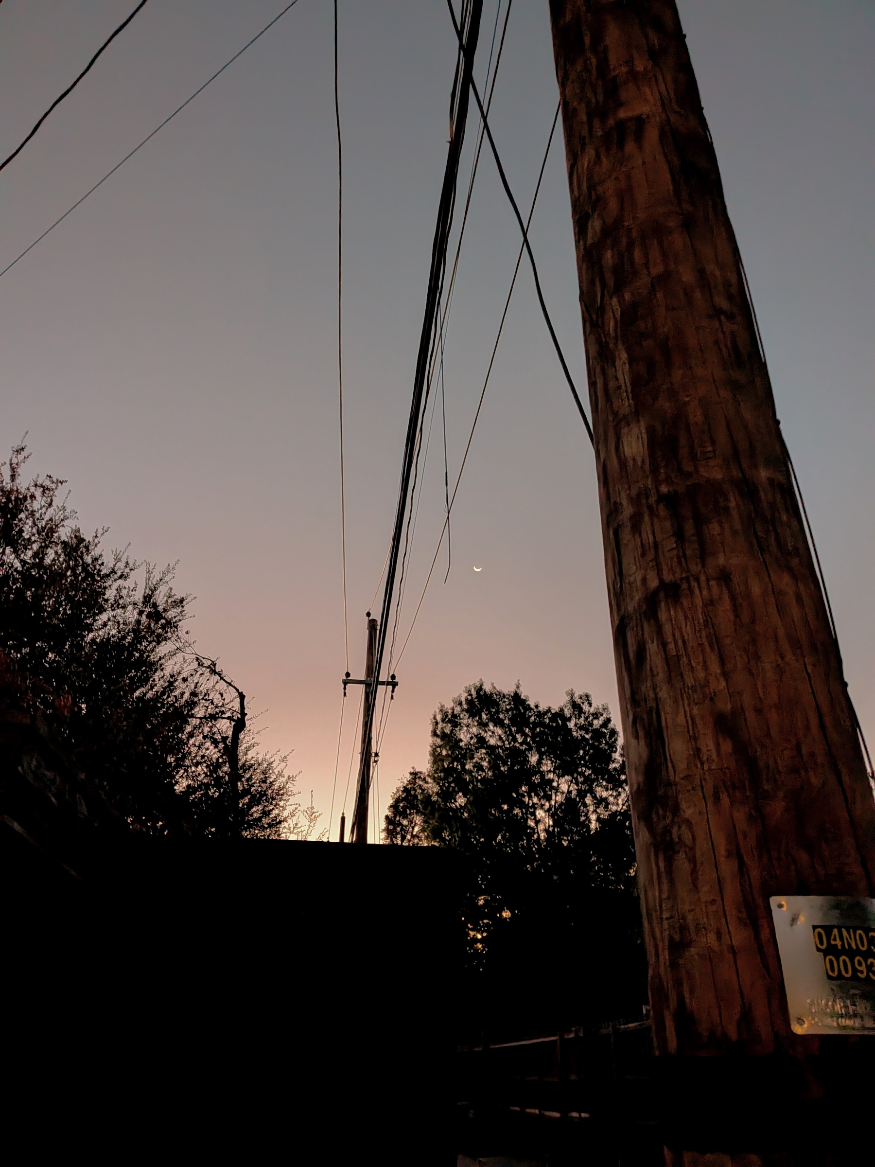 electric wires and a crescent moon at sunrise