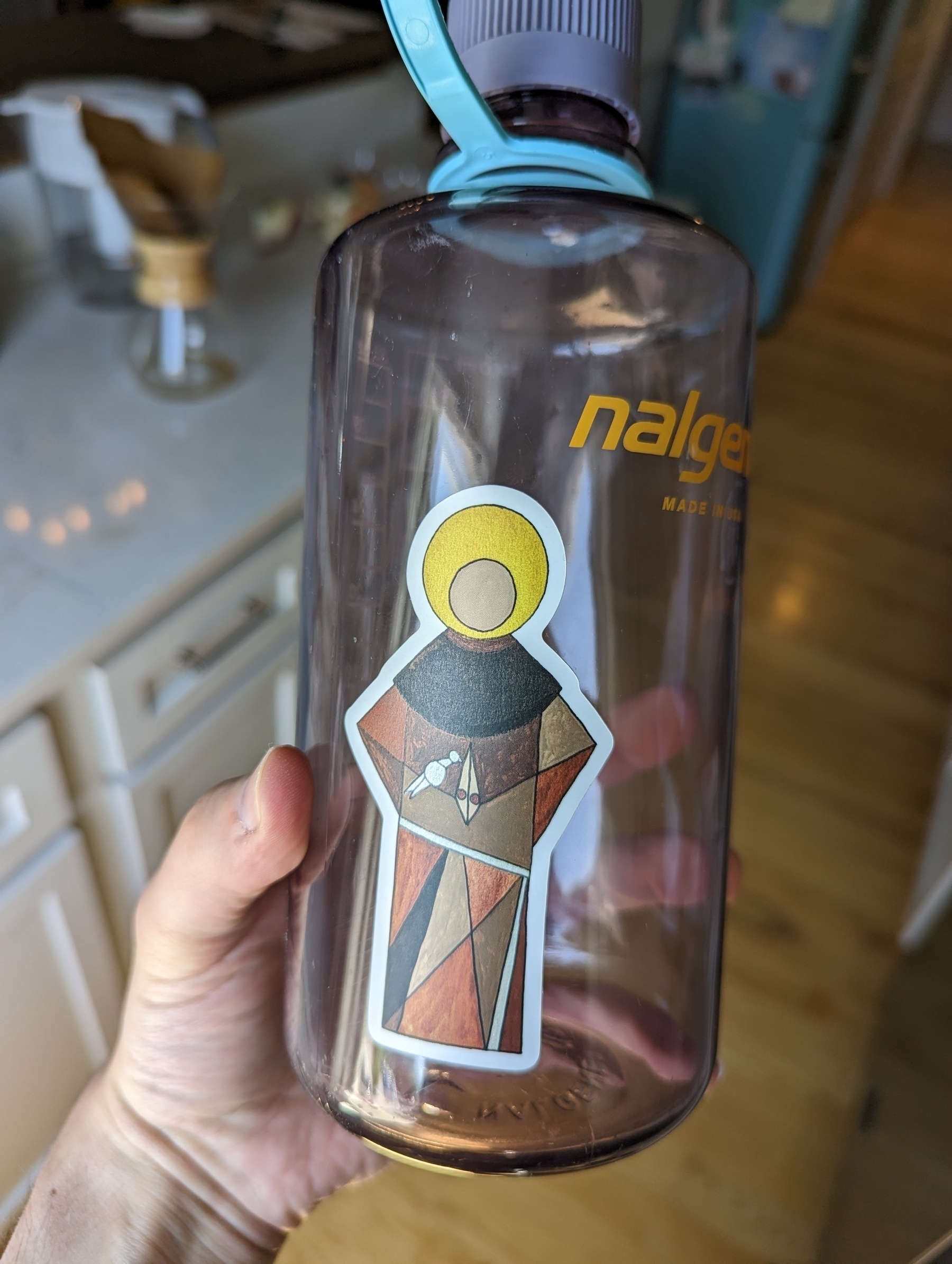 A minimalist sticker of Saint Francis of Assisi on a clear, Nalgene water bottle