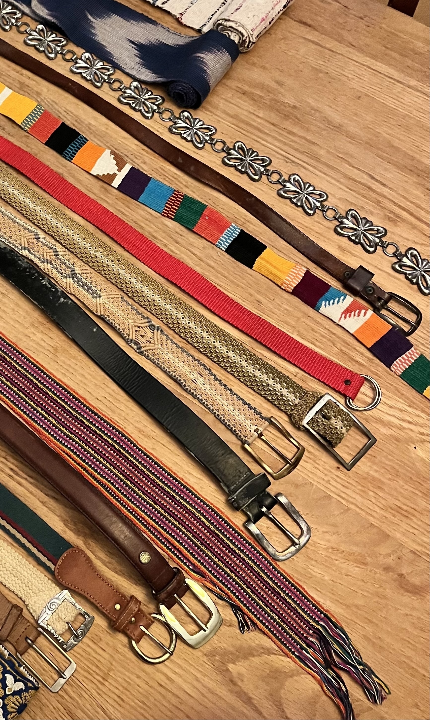 Colorful belts on an oak table running diagonally in the frame