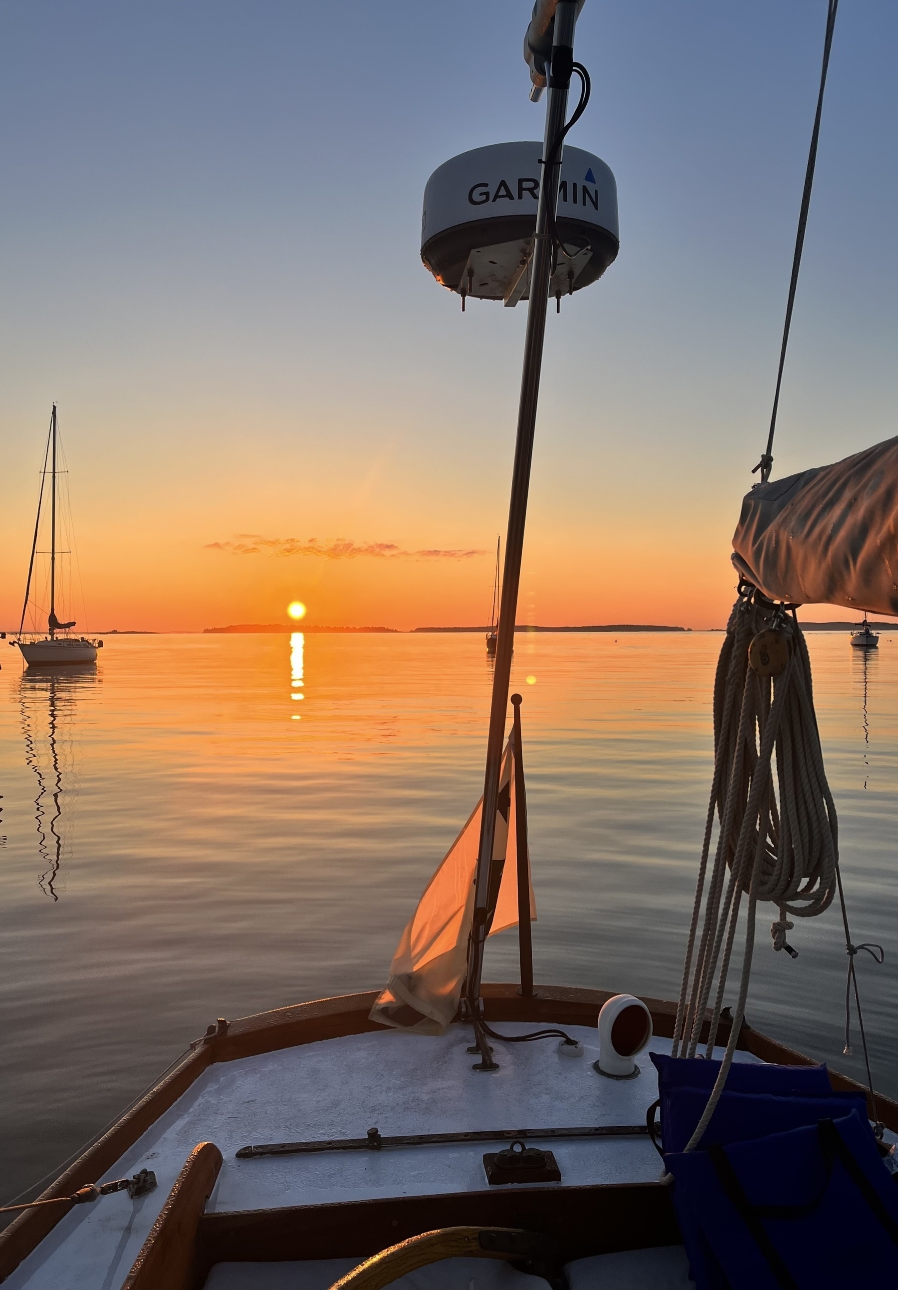 Sunrise over the water from the stern of a sailboat. 