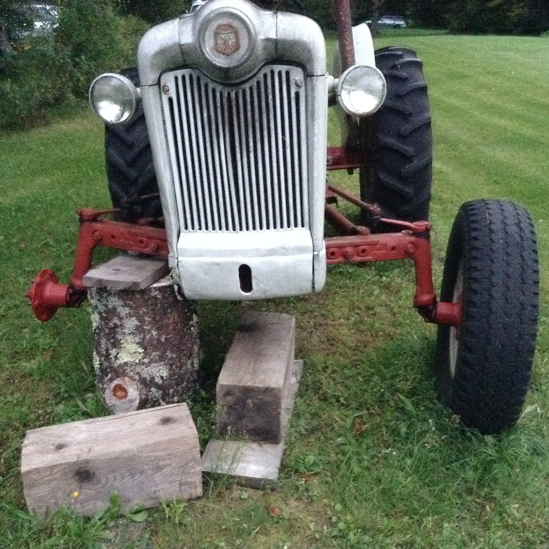Front view of a ford tractor on blocking missing a front wheel. 