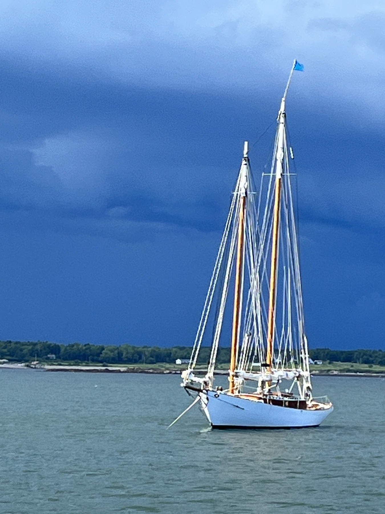 White schooner with dark thunderstorm clouds  in the background 