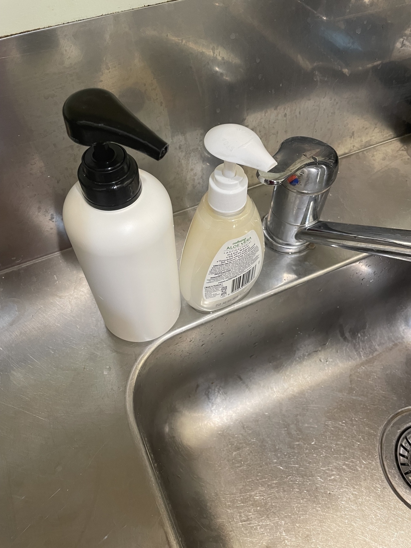 A small pump hand soap container containing hand soap. To its left, a large, white hand pump container containing dish liquid.