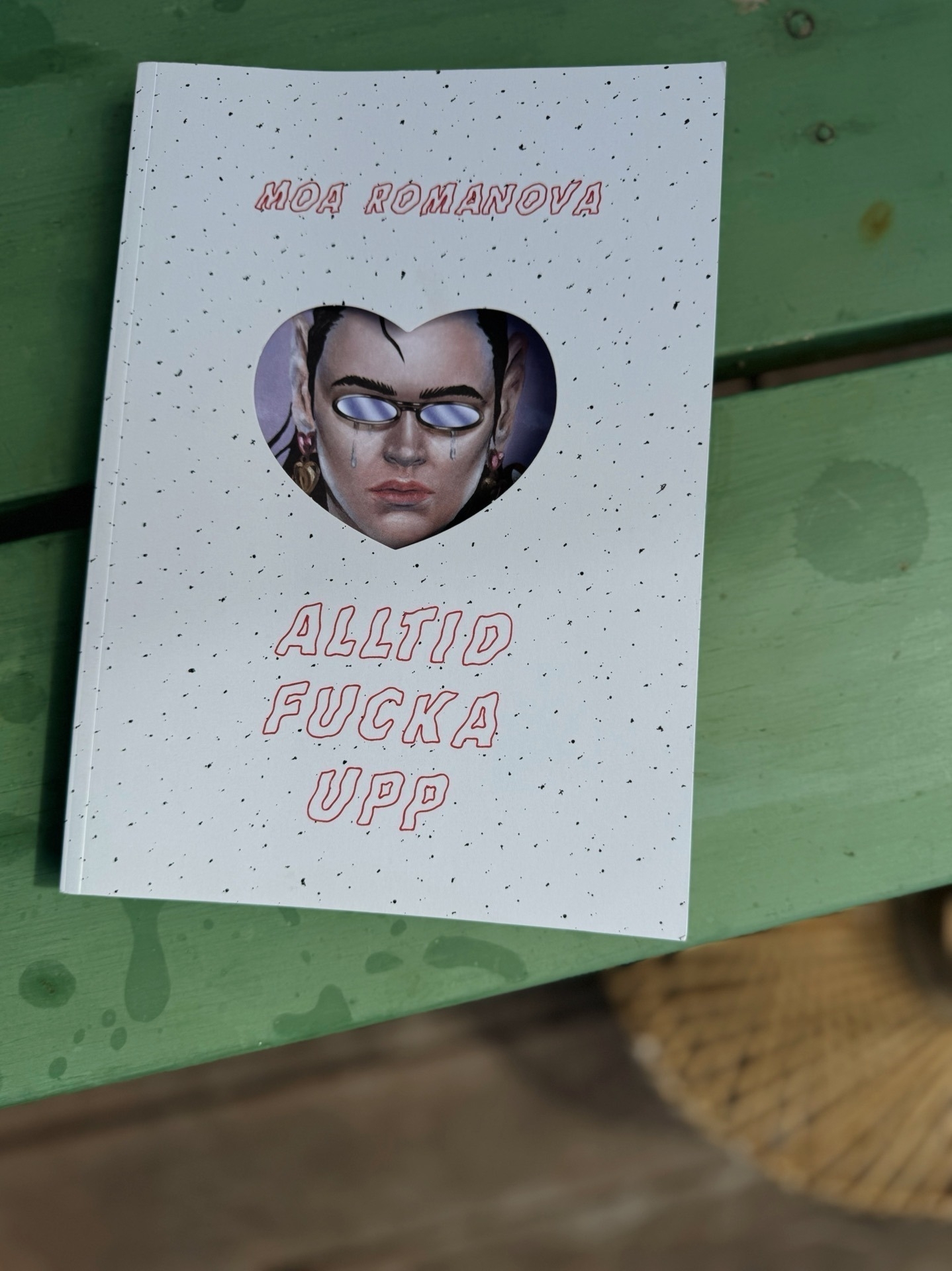 The book’s cover features a heart-shaped cutout showing an illustration of a person’s face with glasses and teardrops. The title is written in red, capitalized letters.