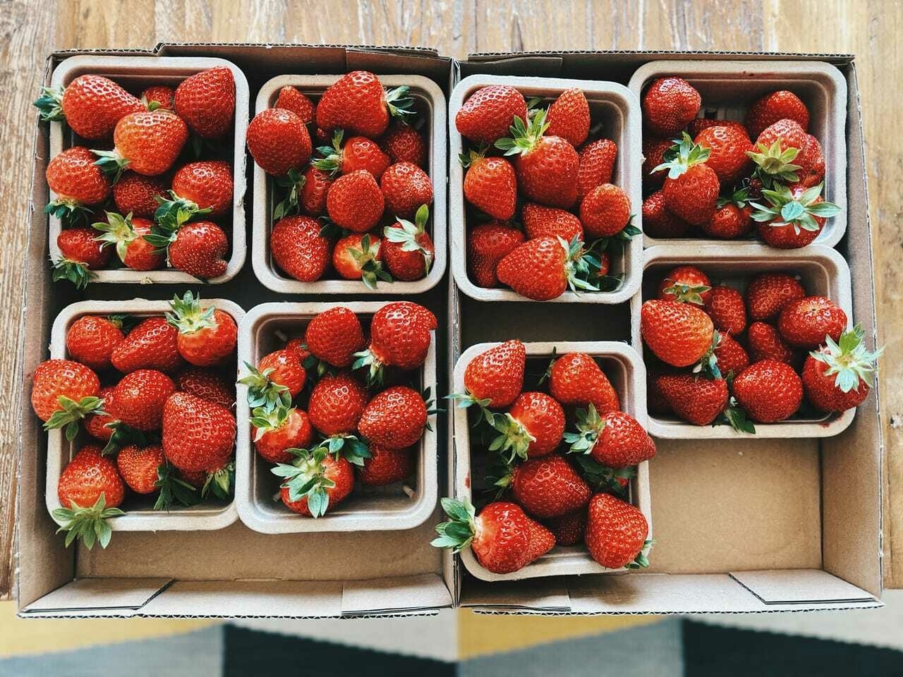 Eight cartons of fresh, yummy looking, strawberries in a cardboard box.