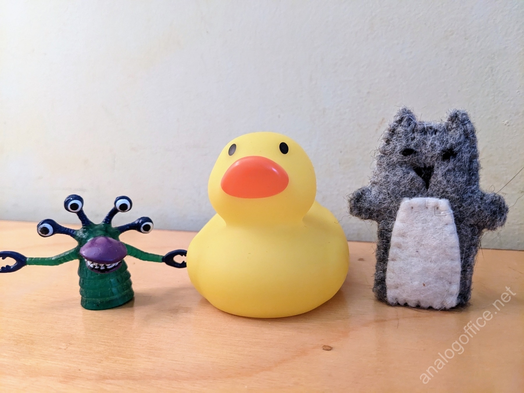 rubber duck bath toy next to a monster finger puppet and a cat finger puppet