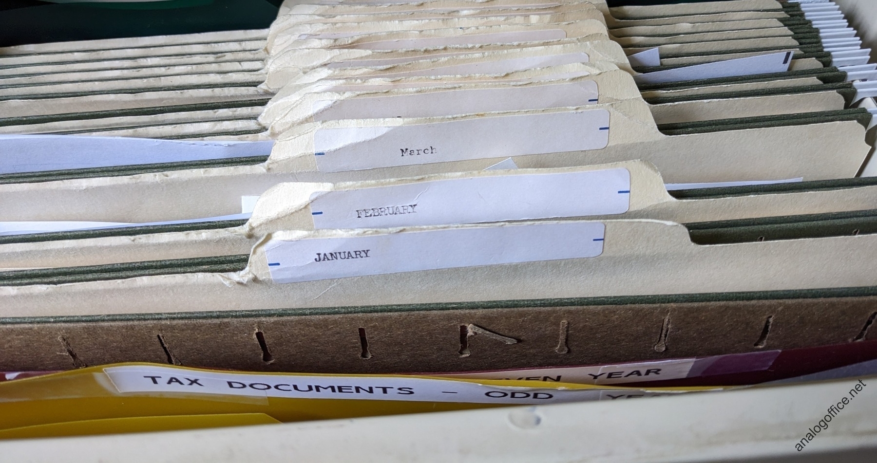 old, beat-up looking file folders in a file drawer with typewritten labels for the months of the year