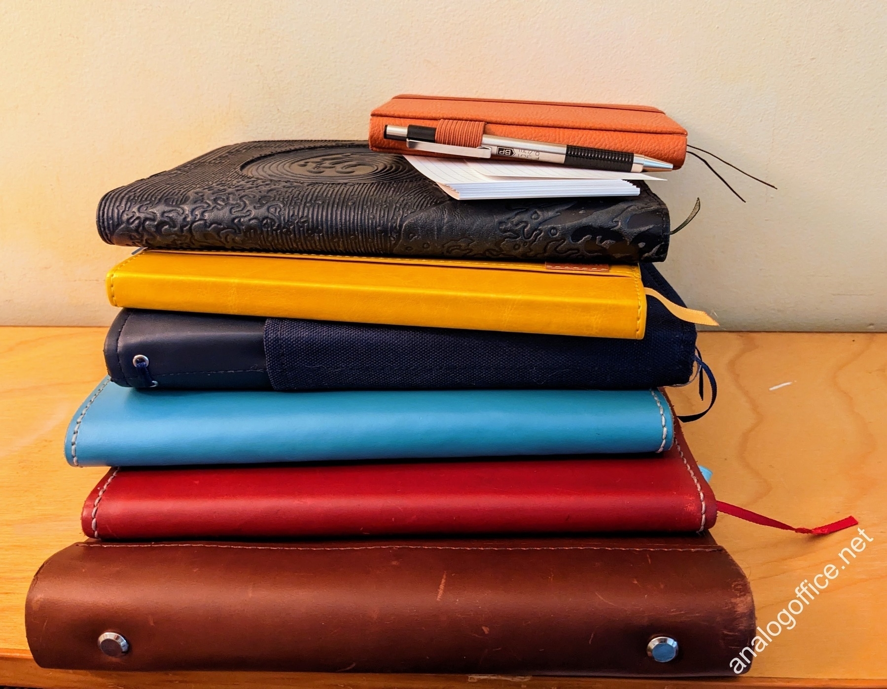 a colorful stack of seven notebooks and some index cards