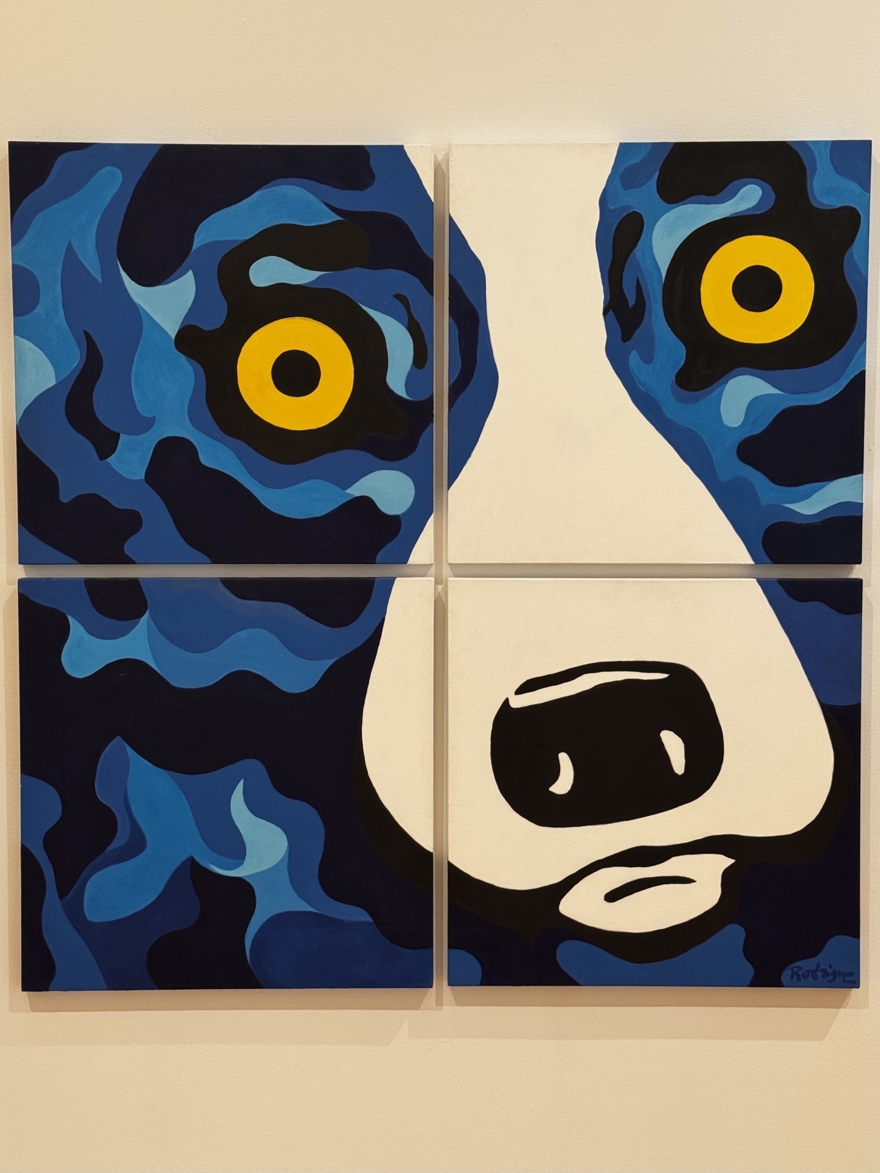 A four-panel artwork features a stylized close-up of a dog's face with blue and black fur, and striking yellow eyes.