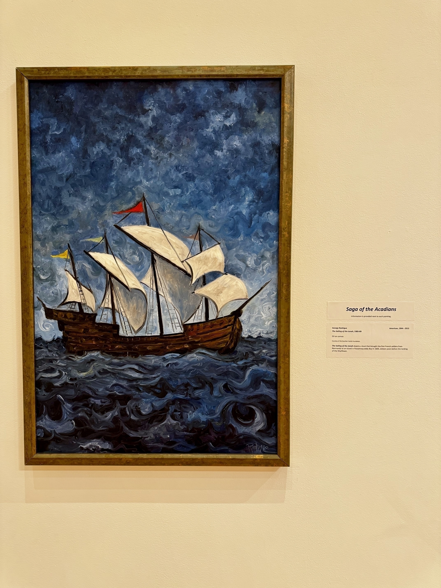 A framed painting depicts a sailing ship navigating through choppy waters under a turbulent, cloudy sky.