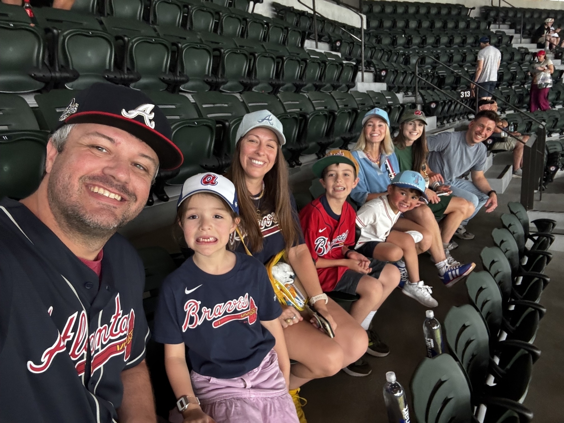 A group of people in Atlanta Braves apparel are seated in a stadium, smiling for a photo.