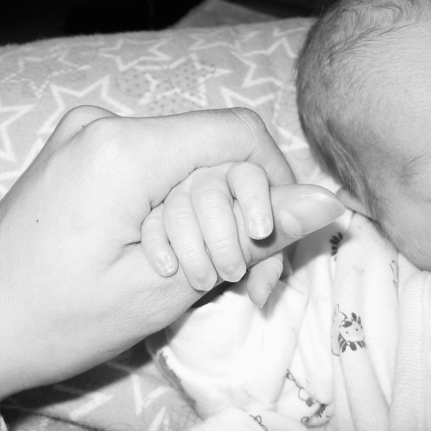 Baby’s hand gripping an adult’s thumb