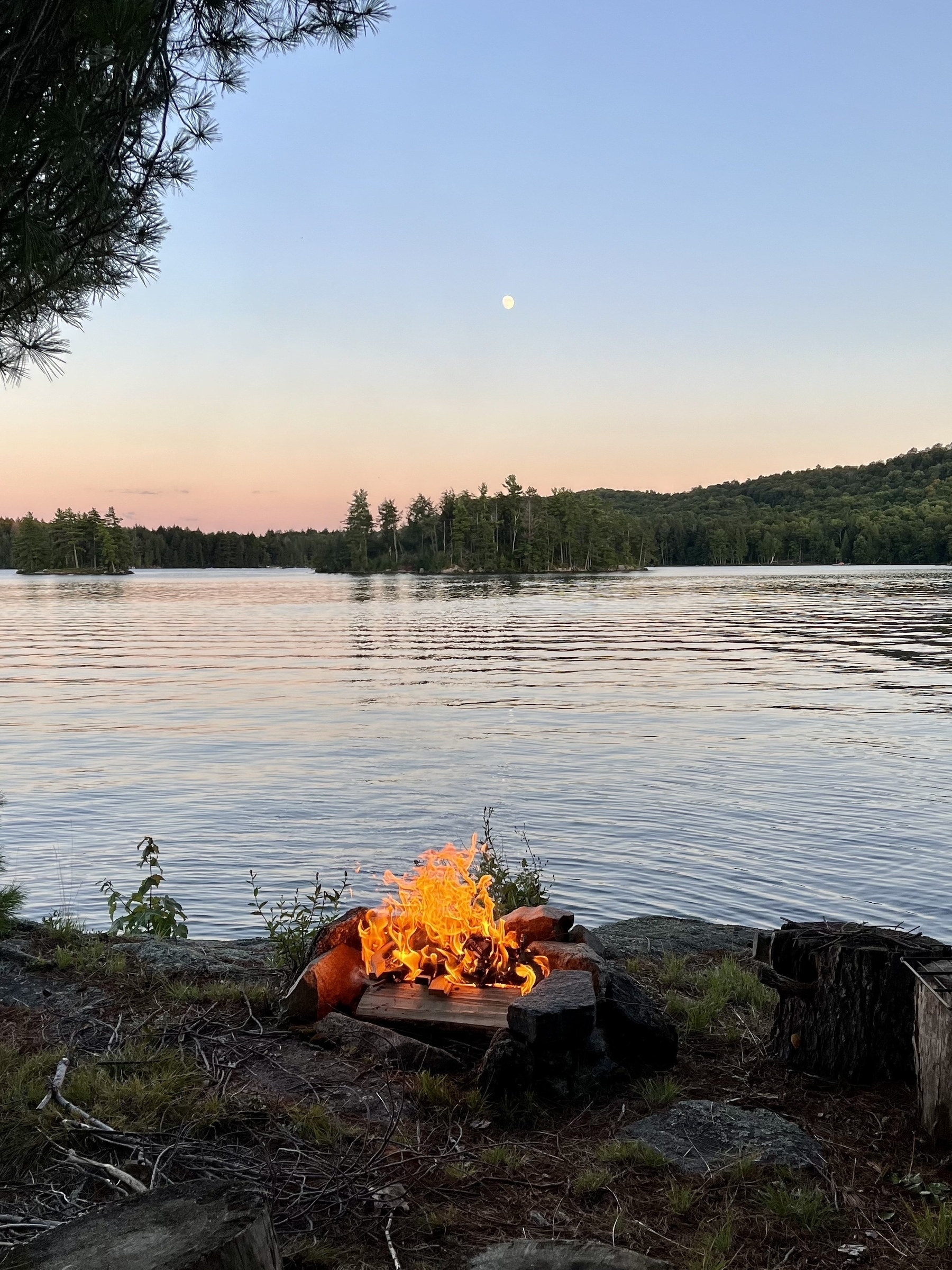 Campfire by lake with moon above