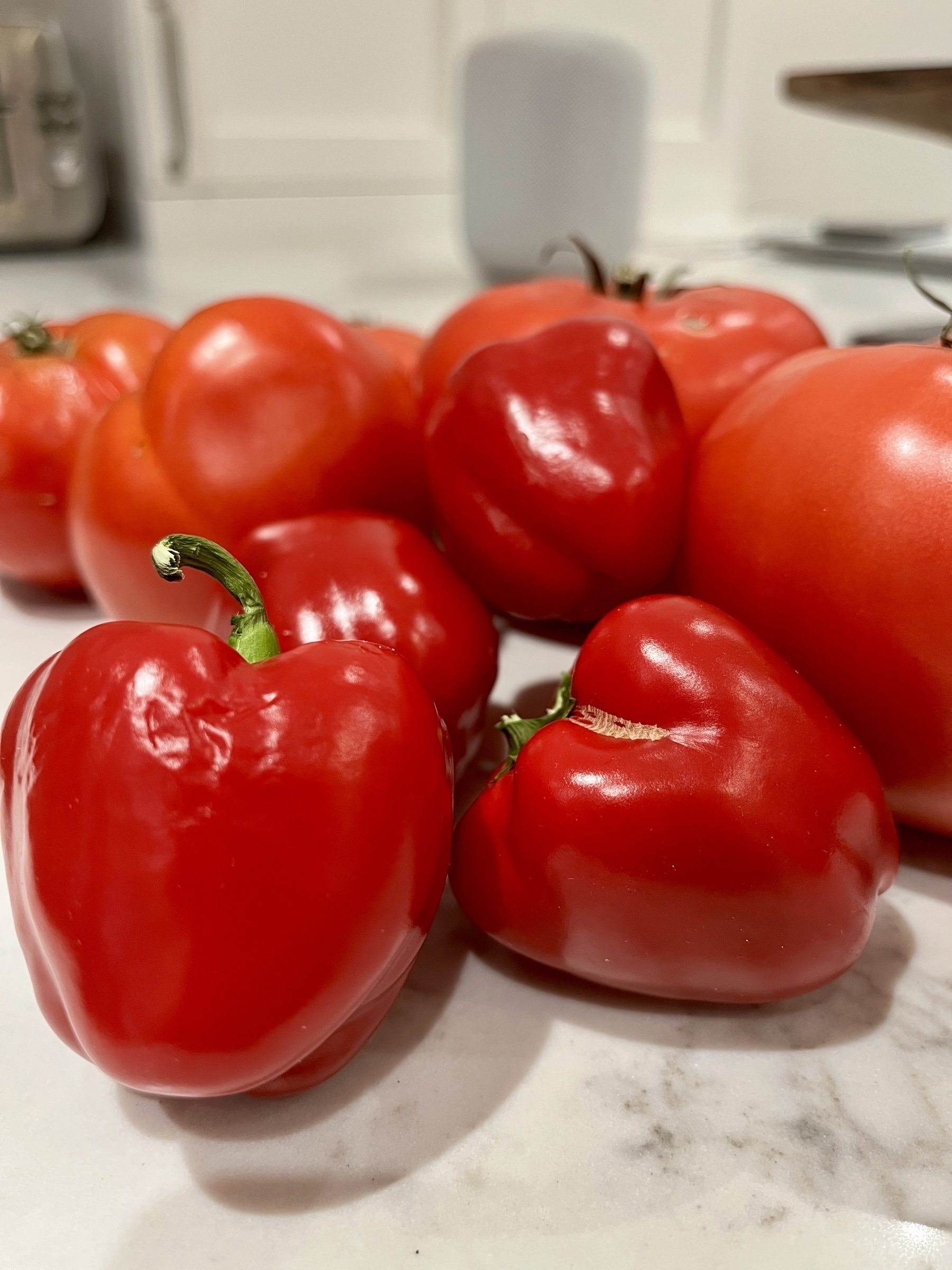 Close up view of red peppers and tomatoes on a counter 