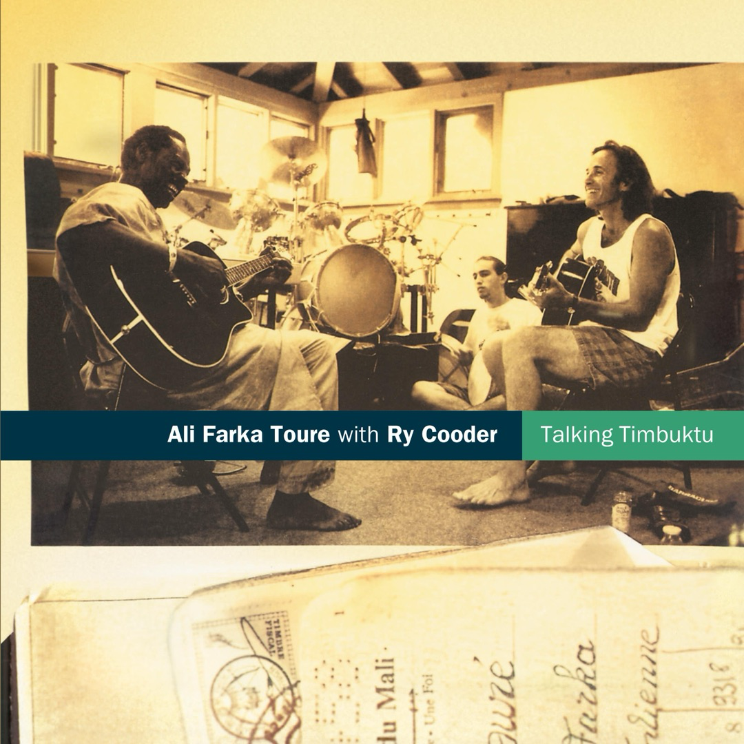 Auto-generated description: Musicians Ali Farka Touré and Ry Cooder are sitting and playing guitars in a relaxed setting, likely related to their album Talking Timbuktu.