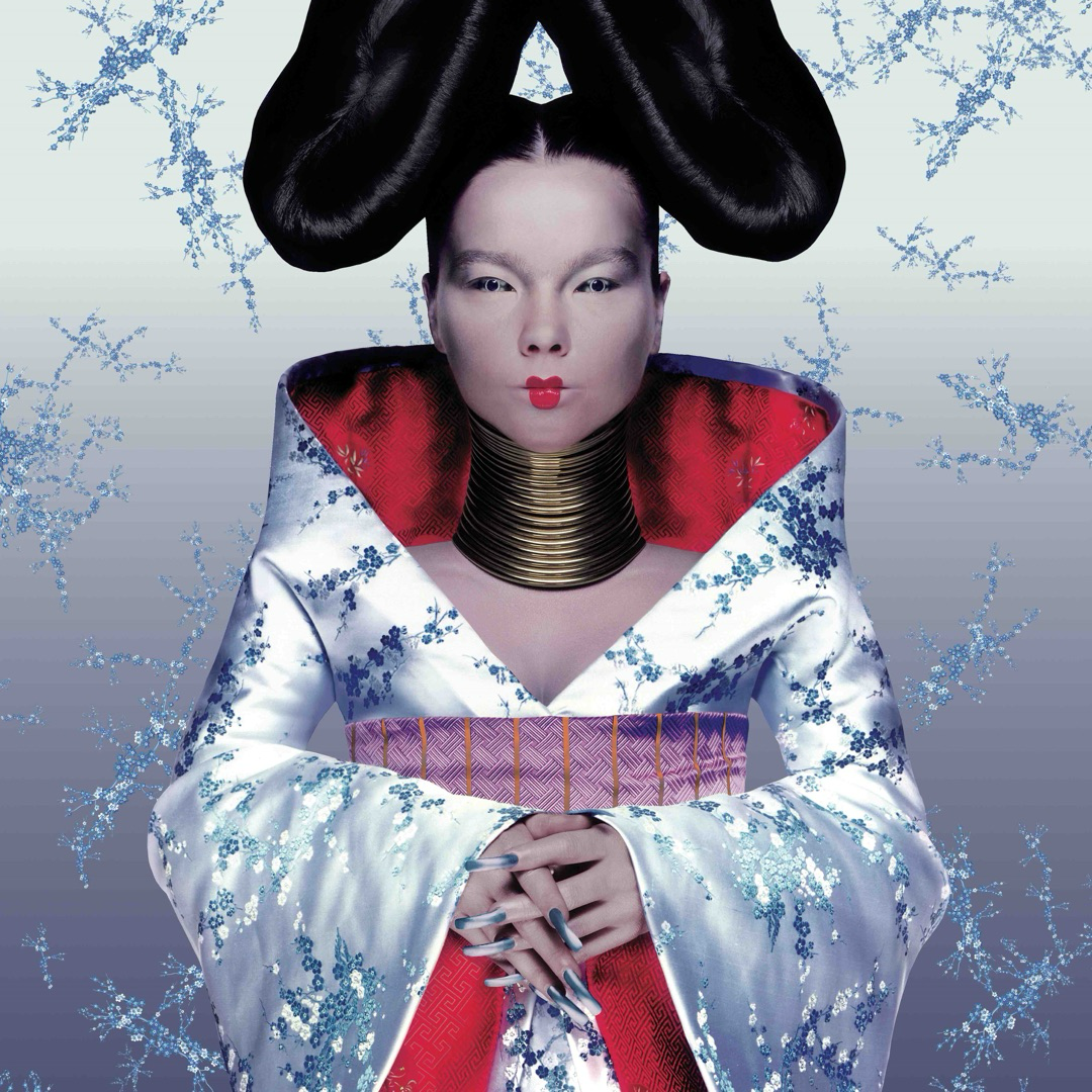 Auto-generated description: A person dressed in a futuristic, ornate robe with a red collar and elaborate hairstyle stands against a backdrop with swirling patterns.