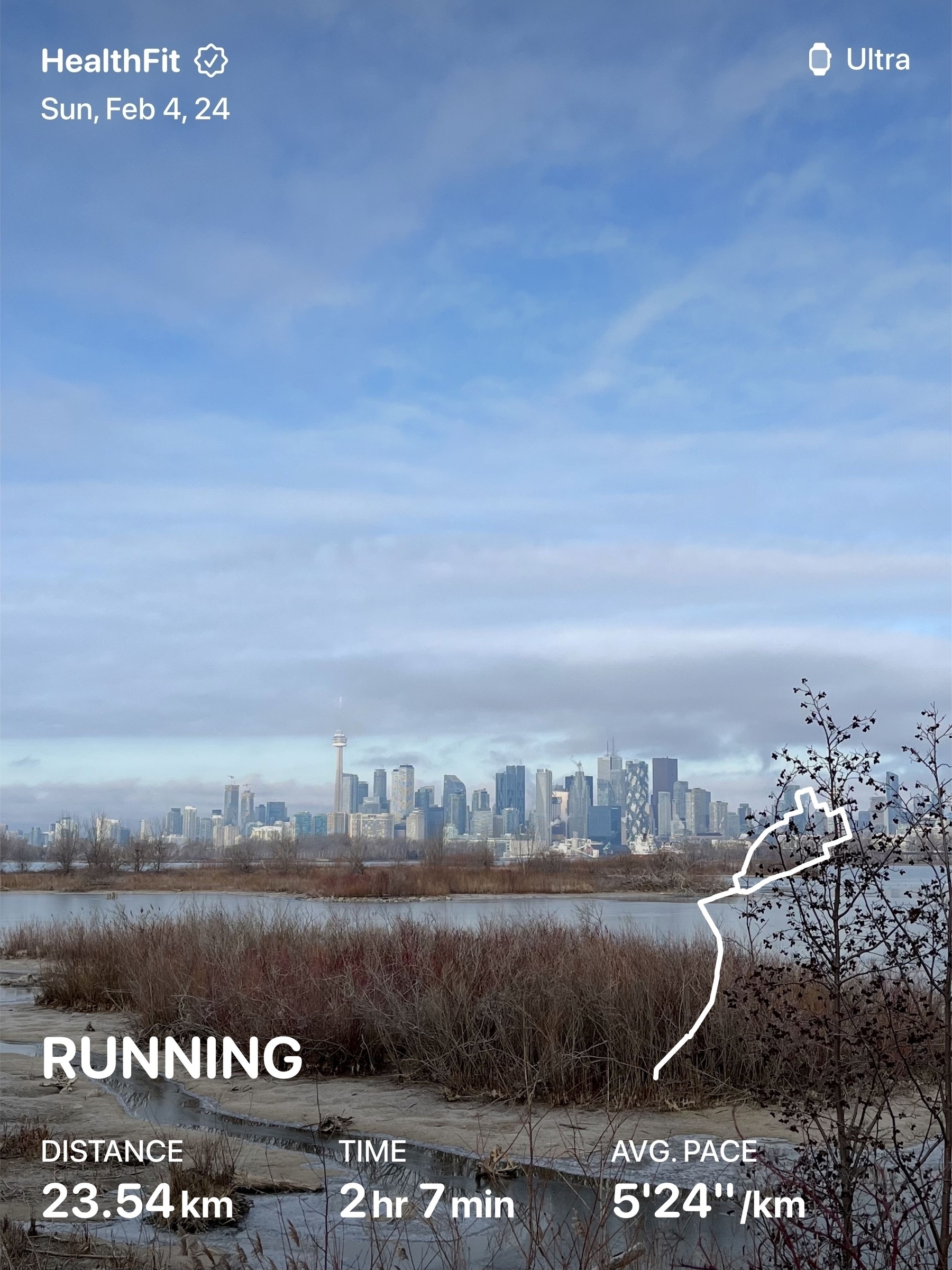 Toronto skyline from across the lake. Overlaid with running stats: 23.54 km in 2h11m
