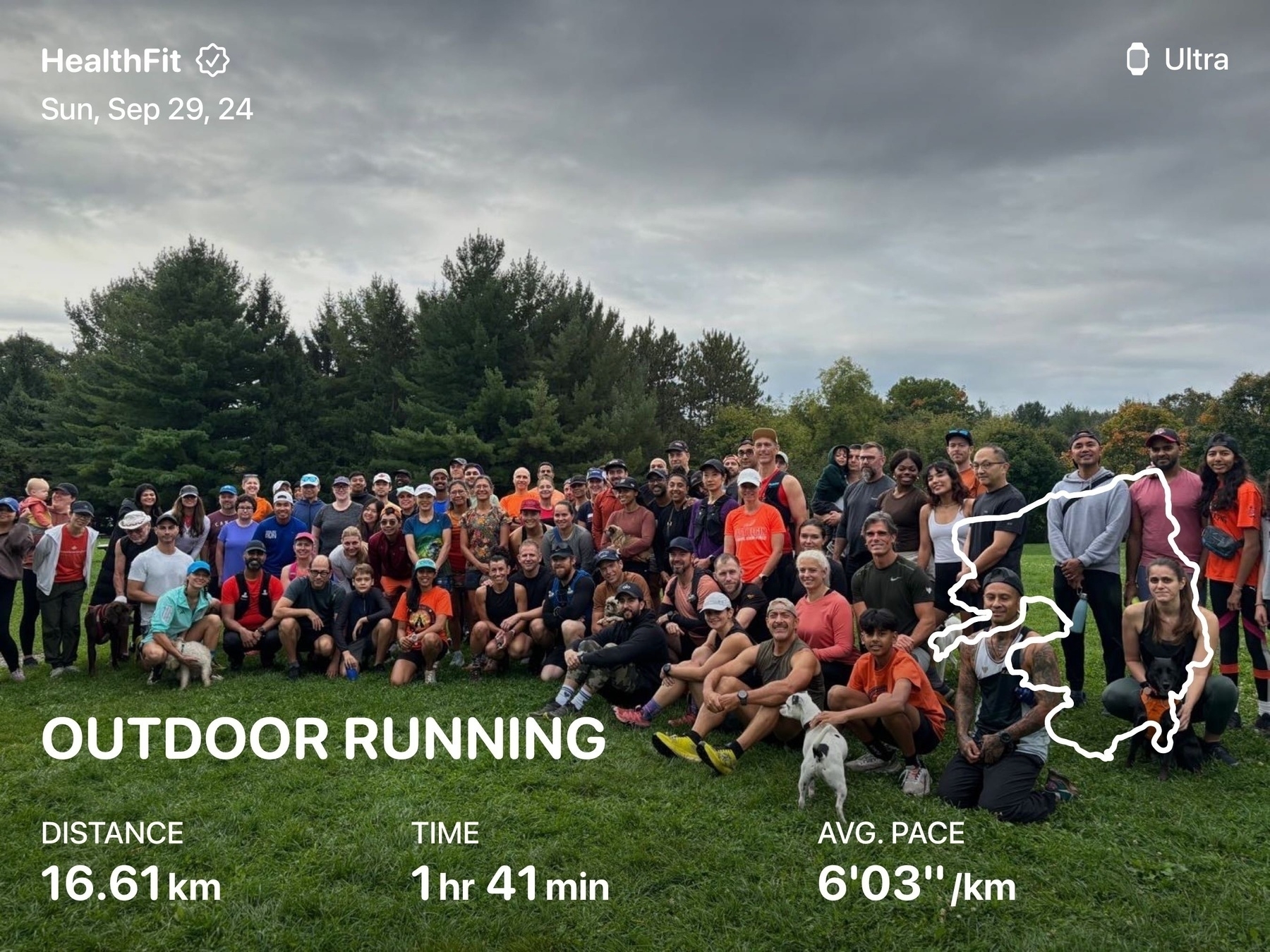 A large group of people is gathered outdoors for a running event, with trees in the background and running statistics displayed.