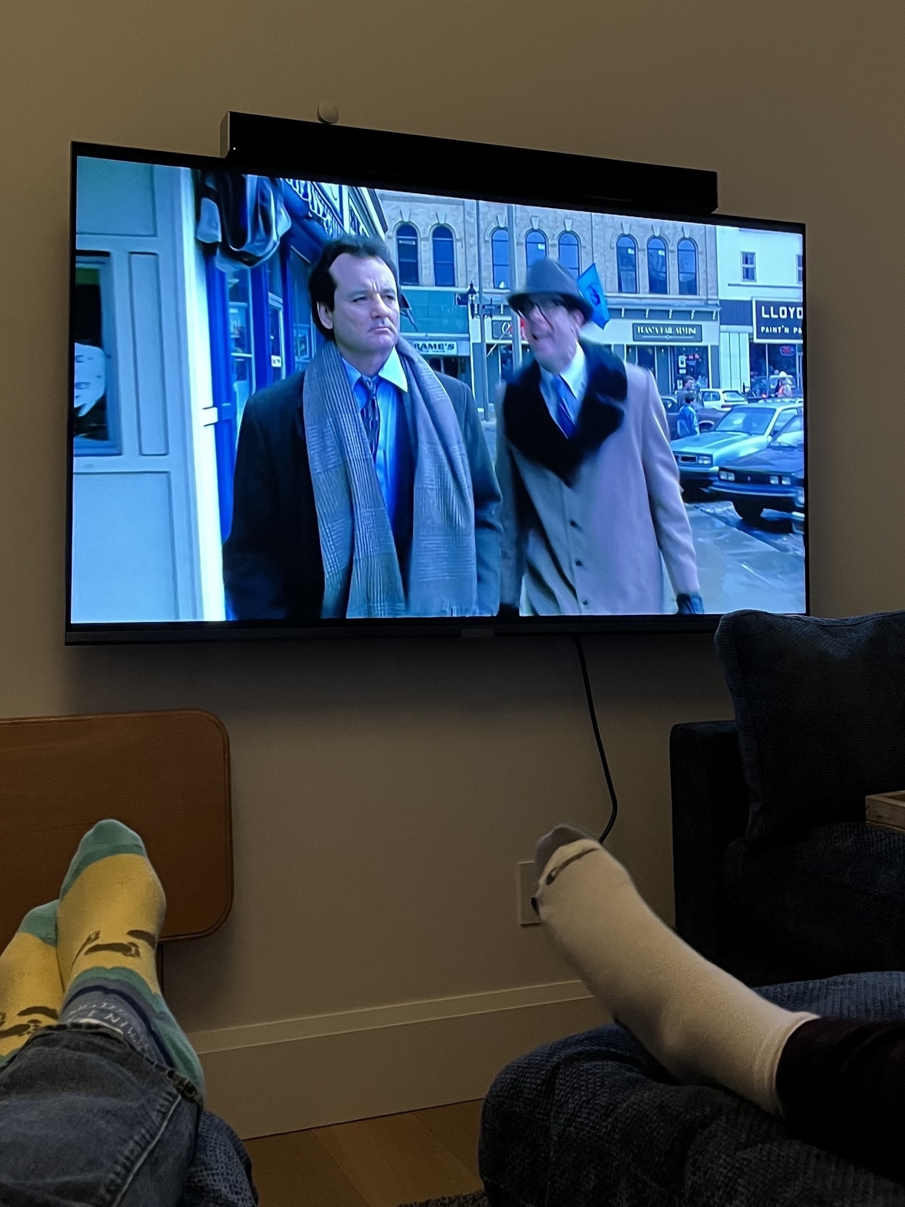 Two people are watching Groundhog Day, as seen from a cozy living room setting.