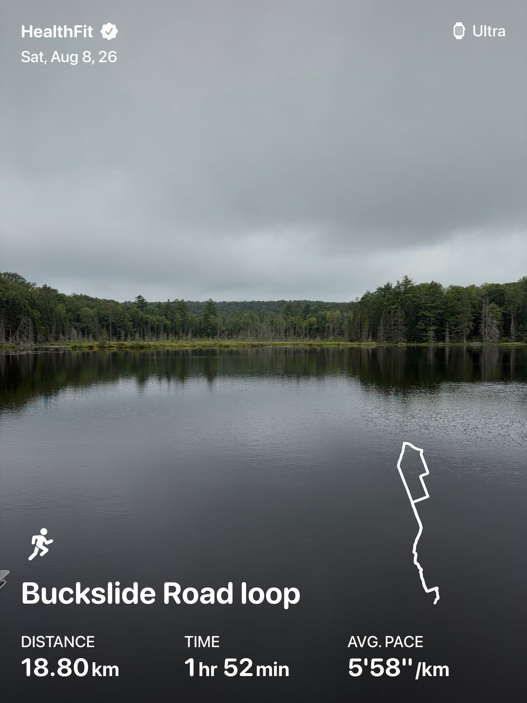A calm, overcast scene shows a large body of water surrounded by dense green trees, with running statistics from a HealthFit app overlaying the image.