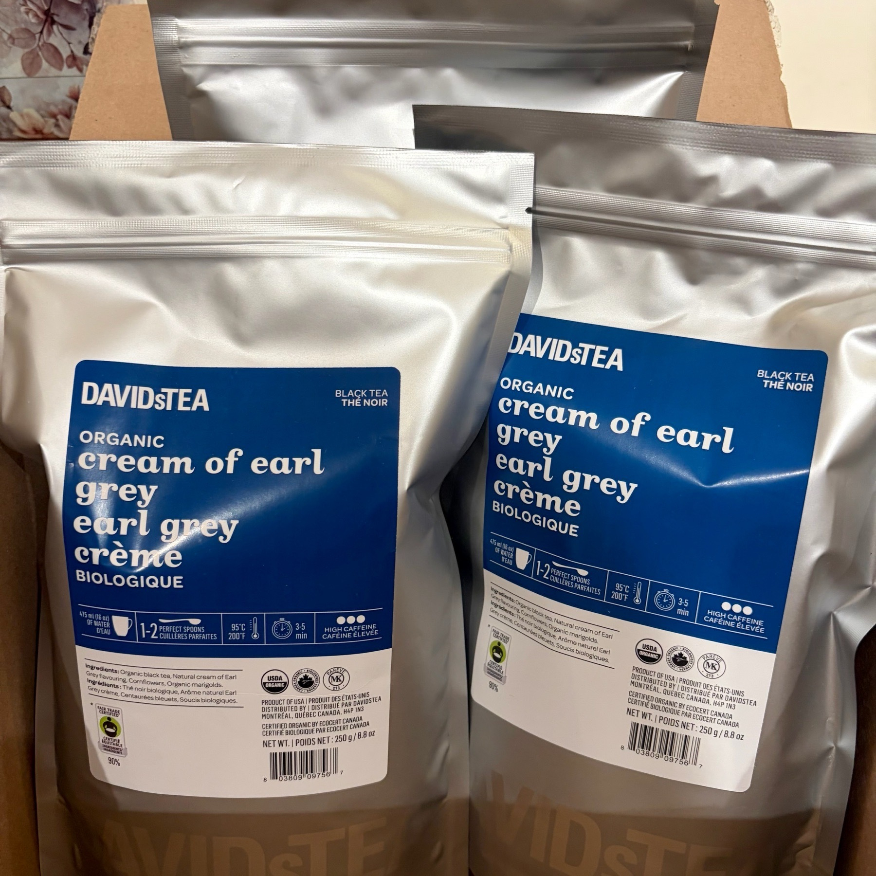Two silver pouches of tea labeled &ldquo;ORGANIC cream of earl grey&rdquo; sit on a wooden surface.