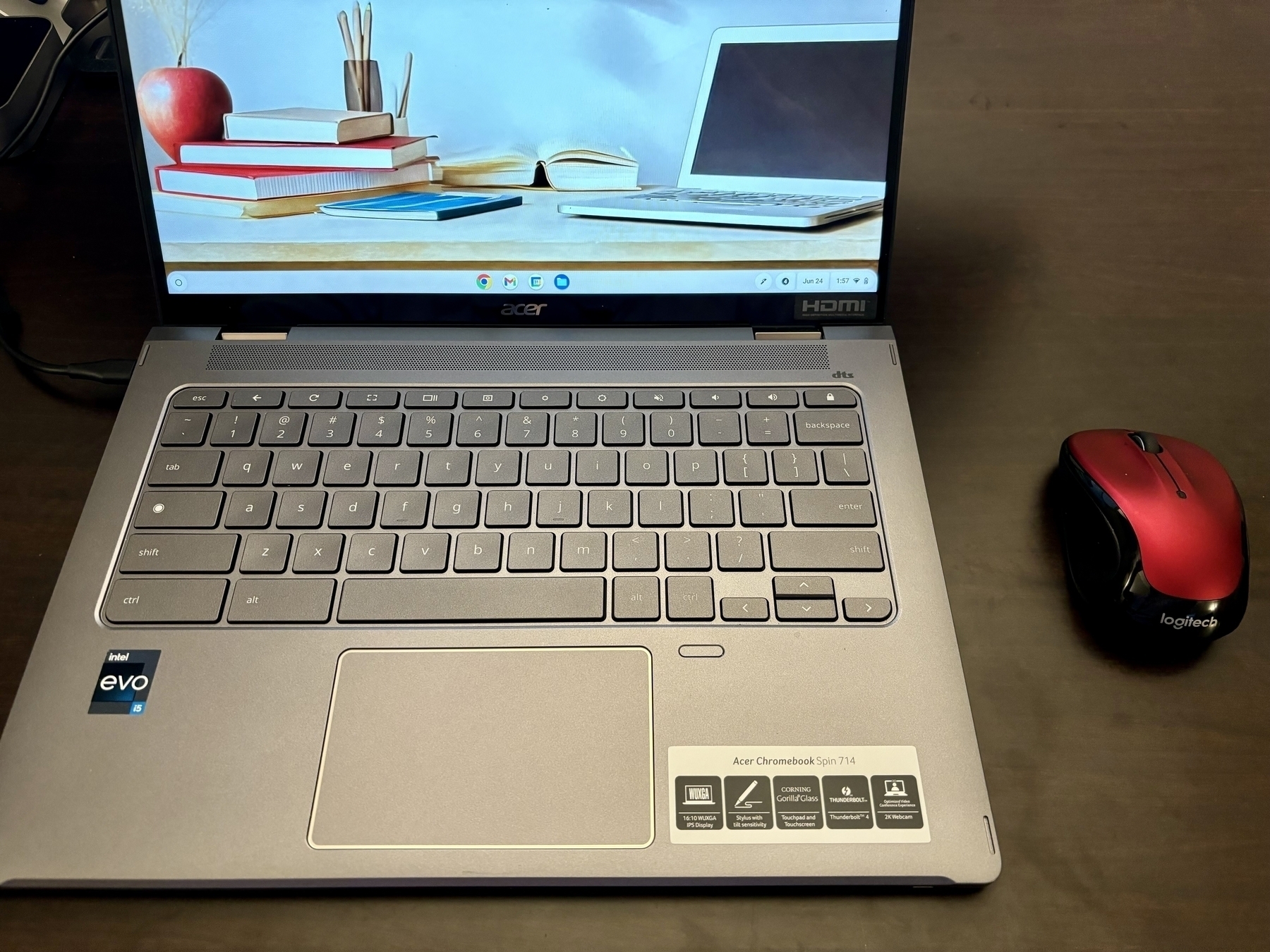 A laptop with a visible screen displaying a workspace background is placed on a dark surface beside a red and black wireless mouse.