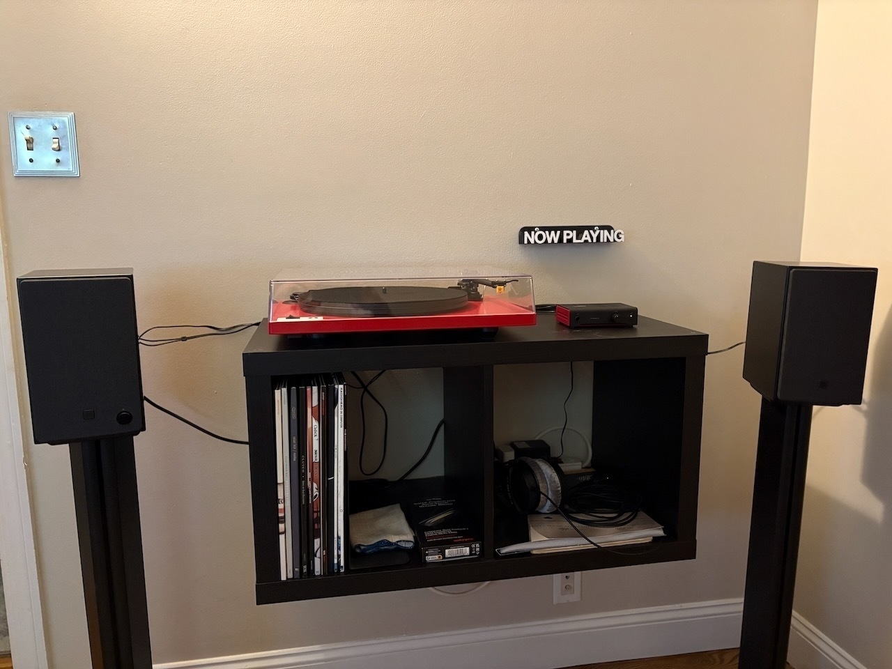 A vinyl record player setup with speakers stands on either side.