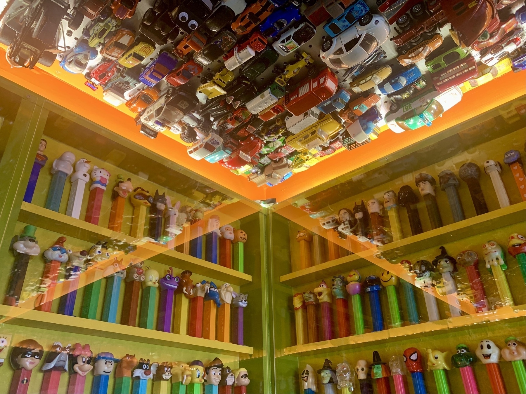 A wall corner with rows of Pez dispensers packed like sardines on both sides and toy cars glued to the ceiling.