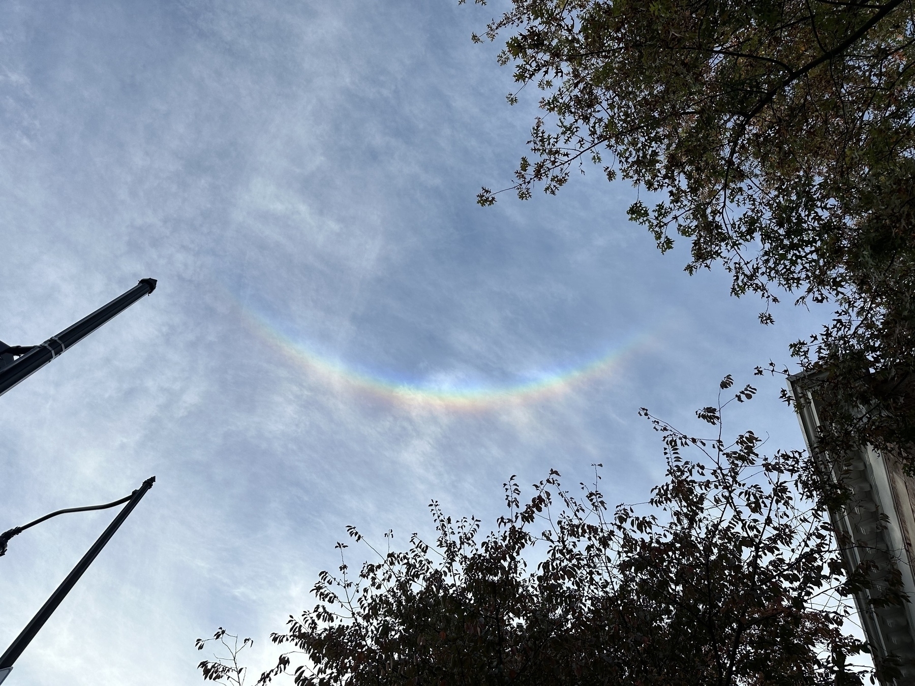 Photo of the sky with a rainbow arc shaped like a smile.