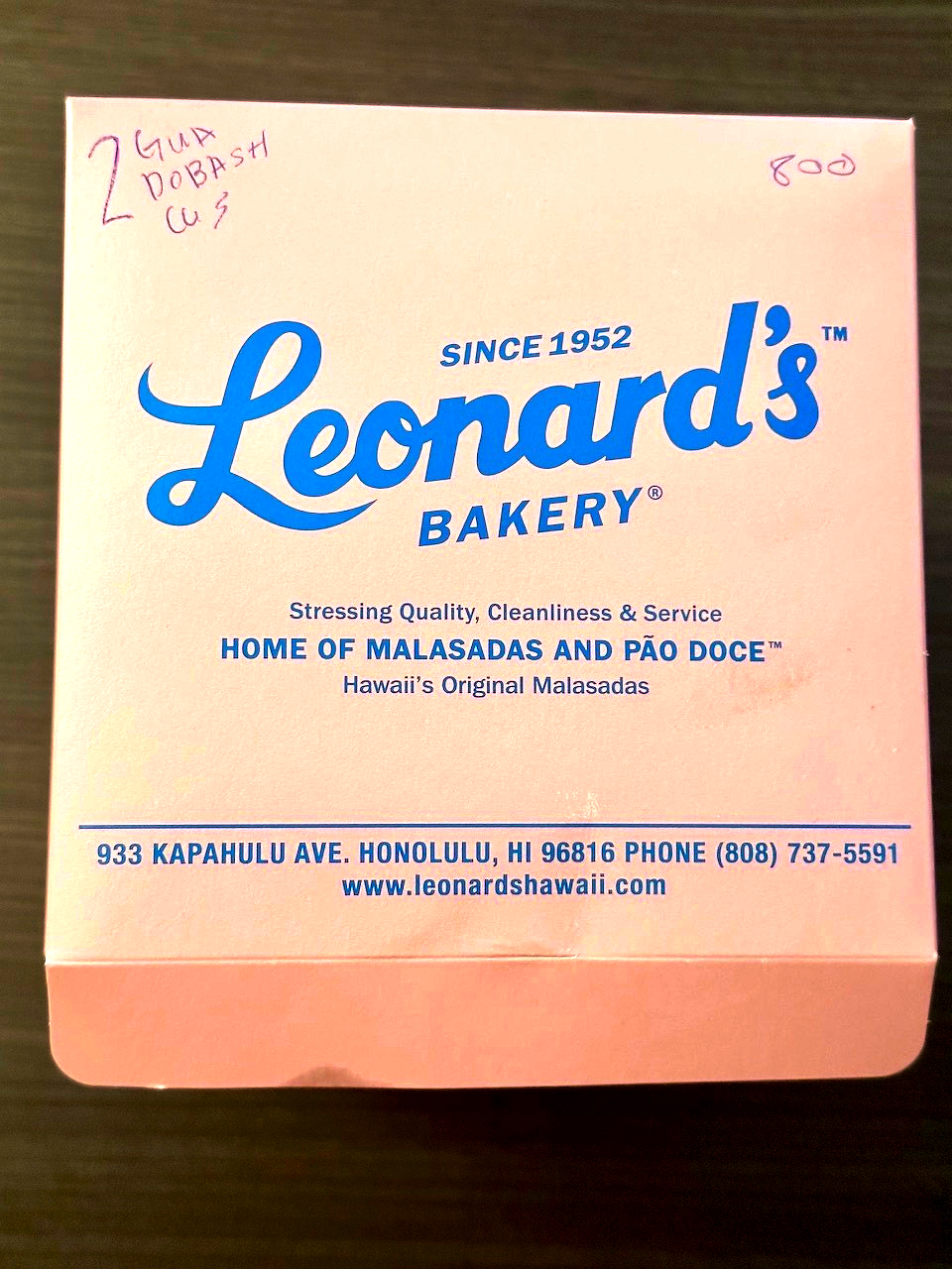 A pink box from Leonard's Bakery contains the text about the bakery's details and emphasizes their malasadas and pão doce.