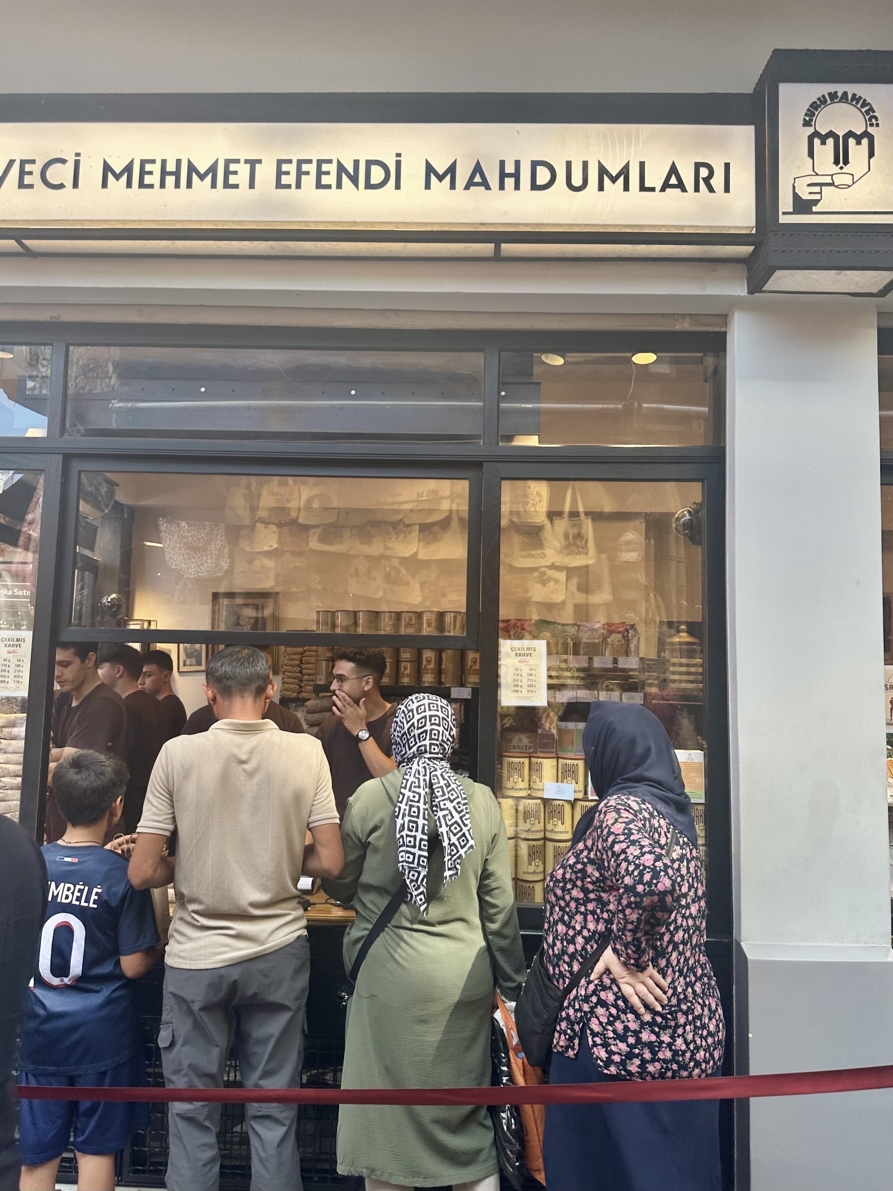 People are standing in line outside a shop called Kurukahveci Mehmet Efendi Mahdumlari.