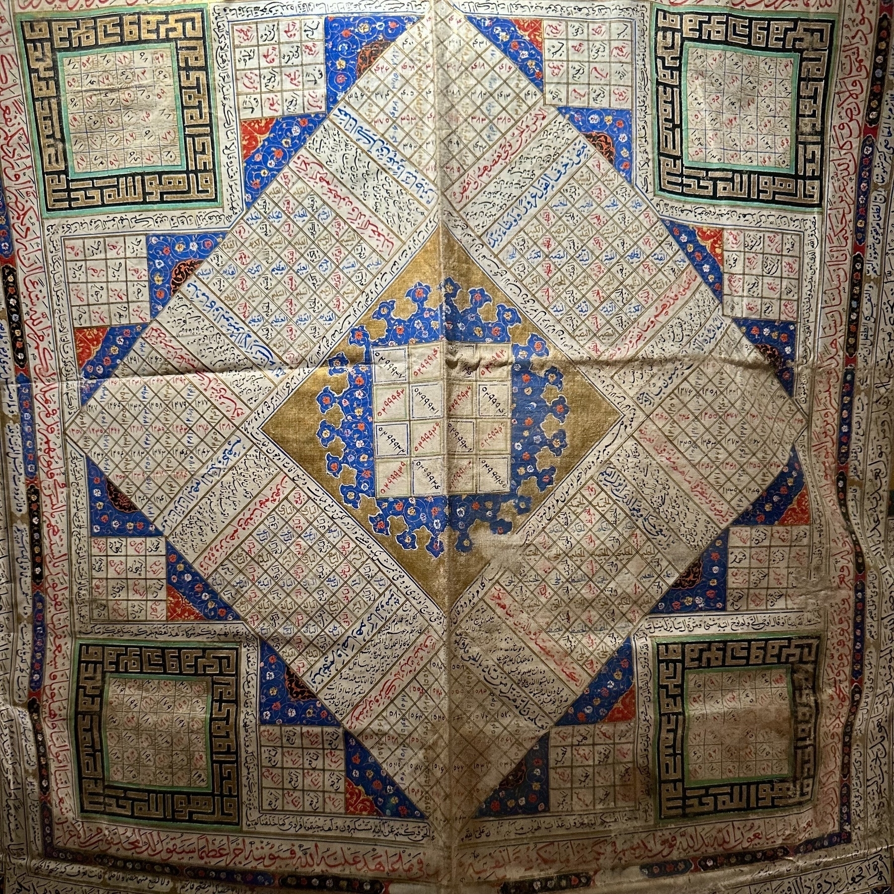 A detailed textile piece featuring intricate geometric patterns, squares, and diamonds with colorful embroidery.