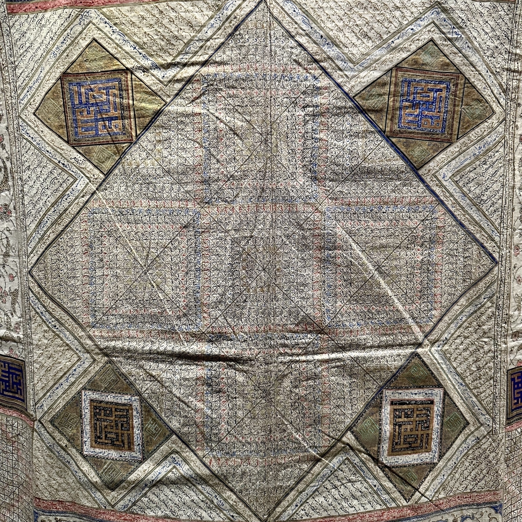 A detailed textile features intricate geometric patterns and a central diamond shape surrounded by smaller square designs, each with unique motifs.