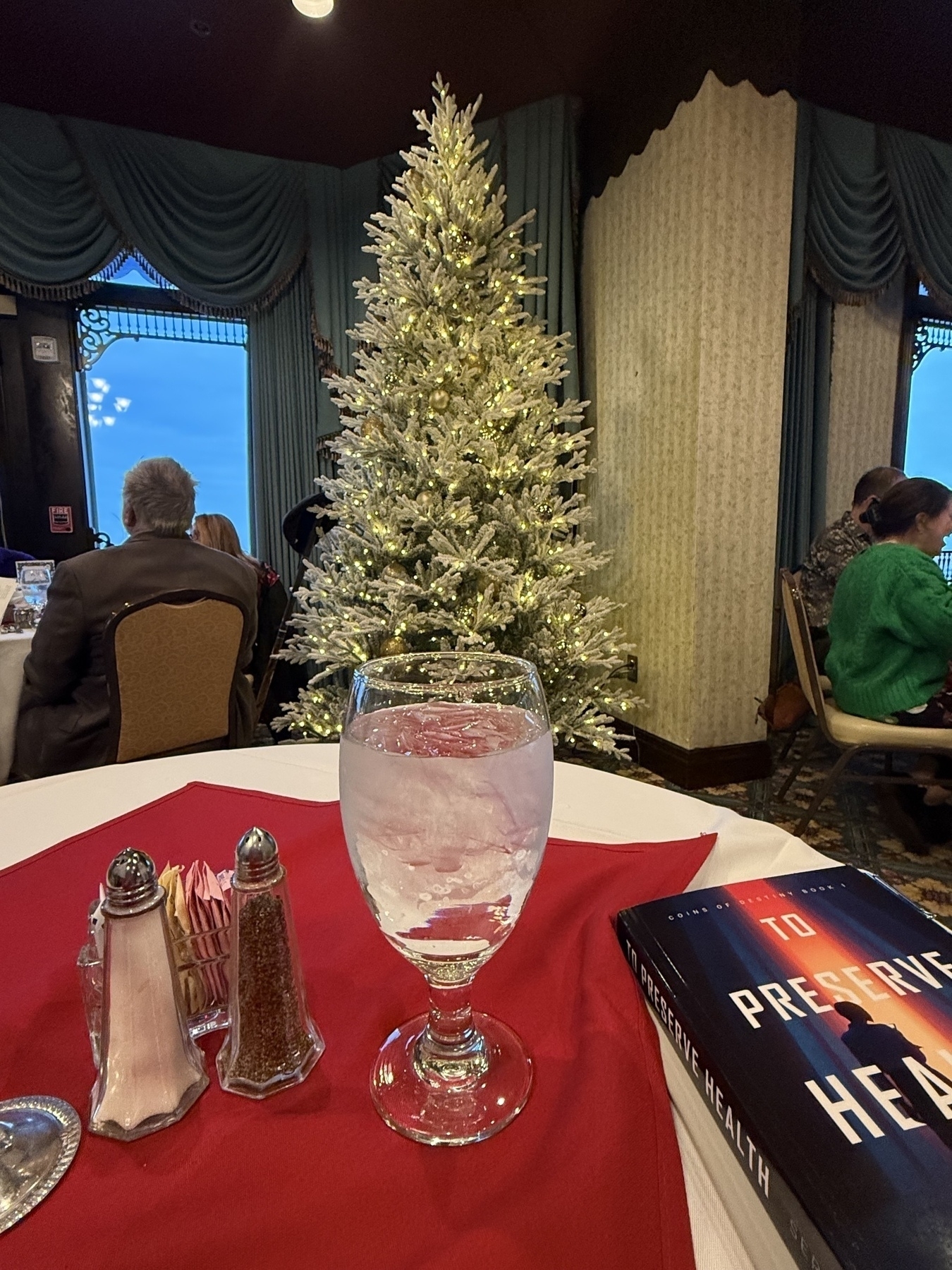 Restaurant table, water, book, and tree