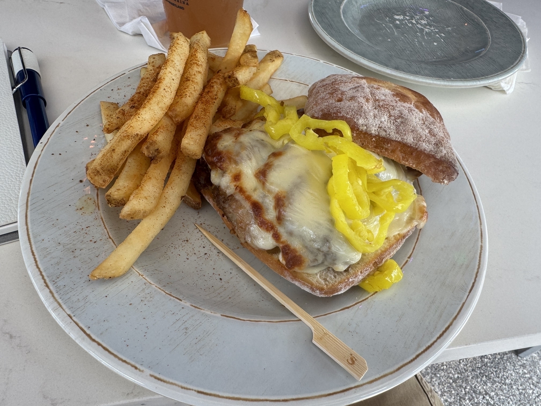 Sandwich with banana peppers and fries. 