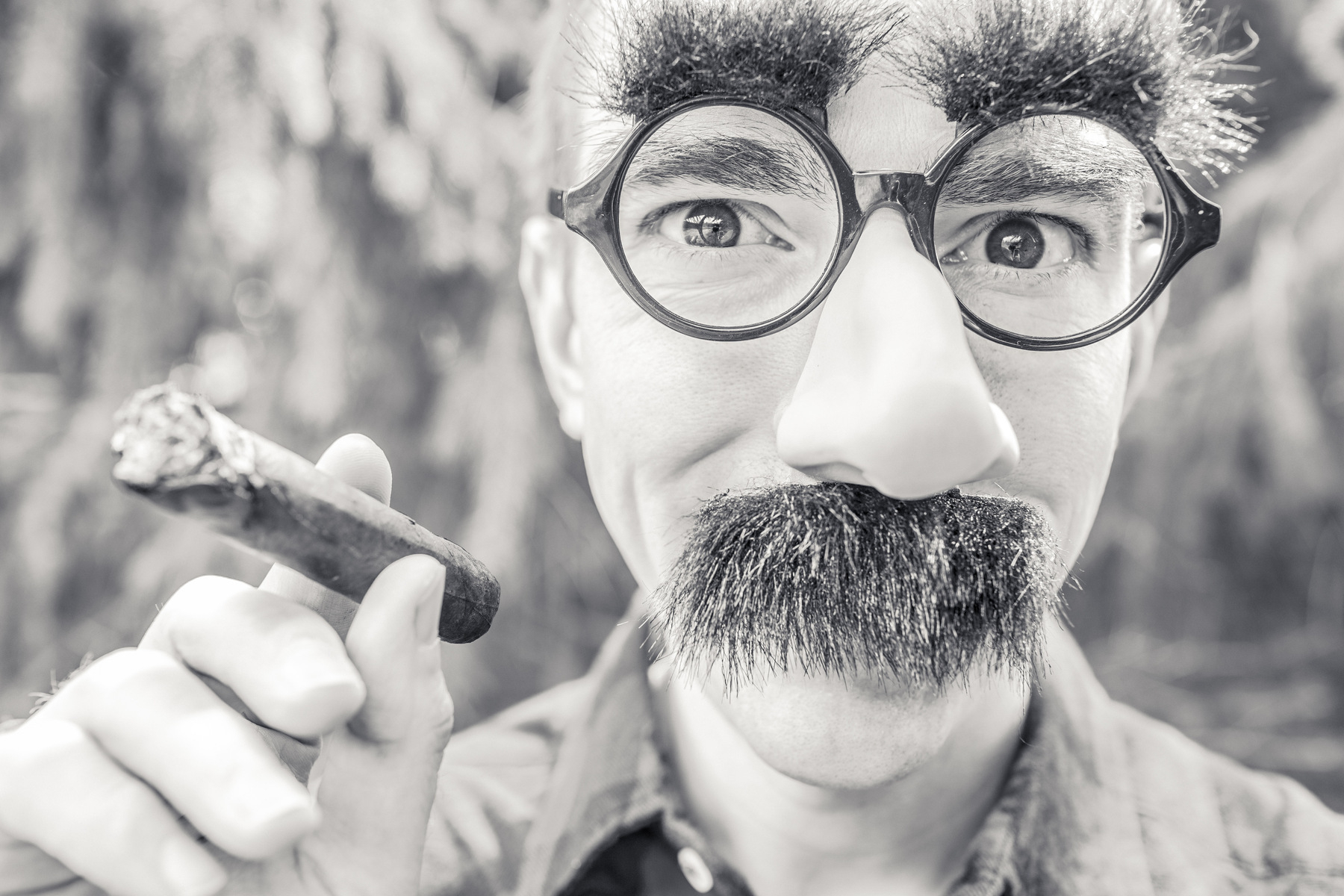 Man with fake mustache and glasses smoking a cigar