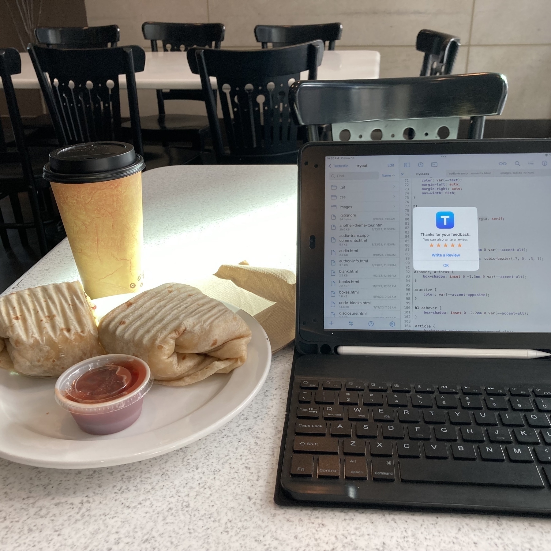 Breakfast burrito, coffee, and an iPad on a small table. 