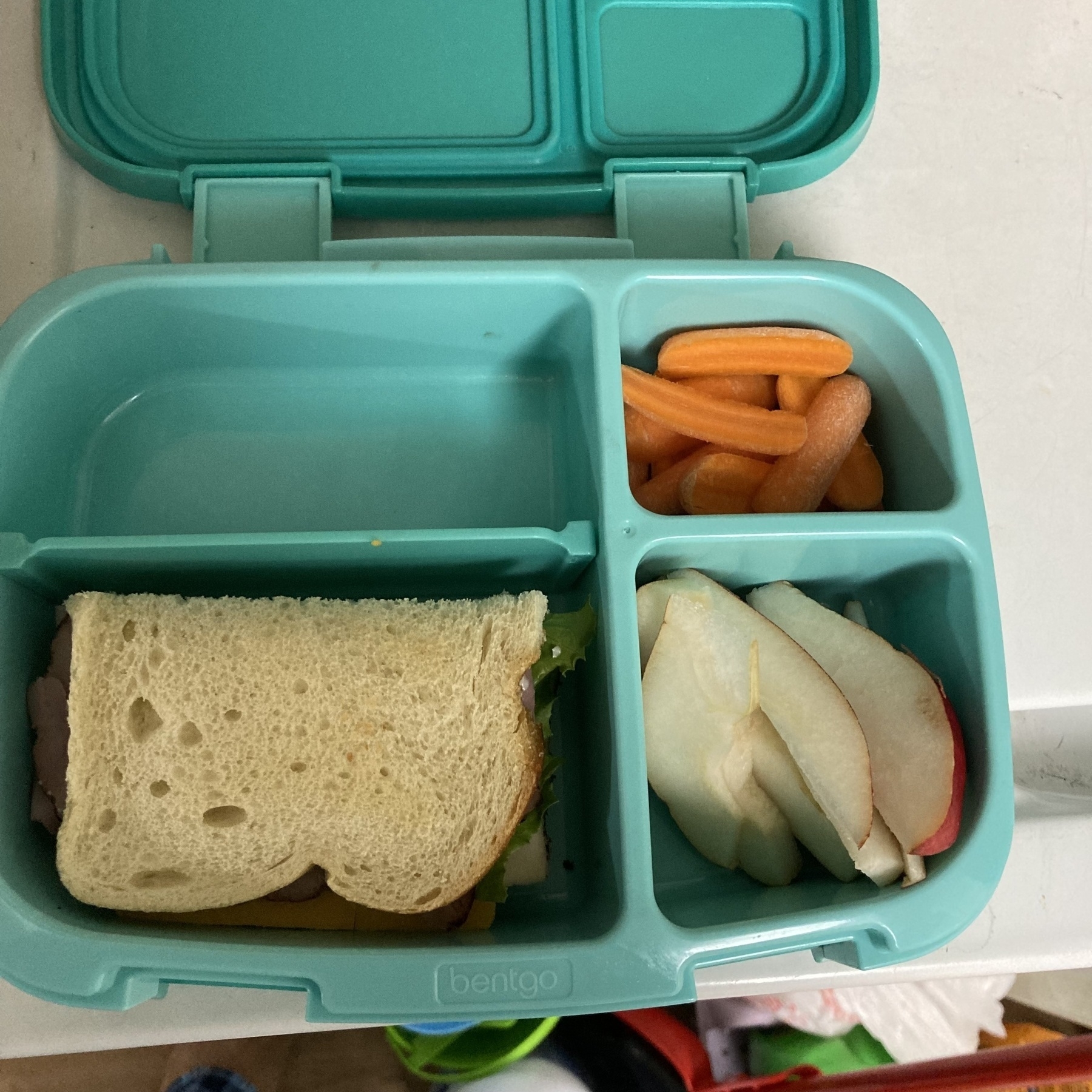 Bento box with sandwich, sliced pears, and slivered carrots. 