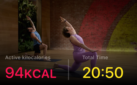 Two people are practicing yoga in a studio, with workout stats shown in the foreground.
