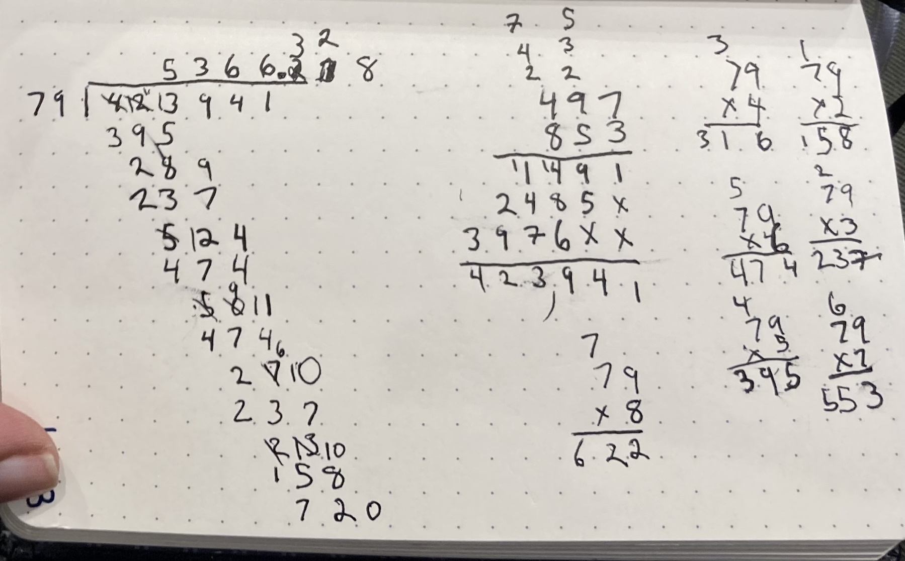 A dotted notebook page with handwritten mathematical calculations and numbers scattered across it.