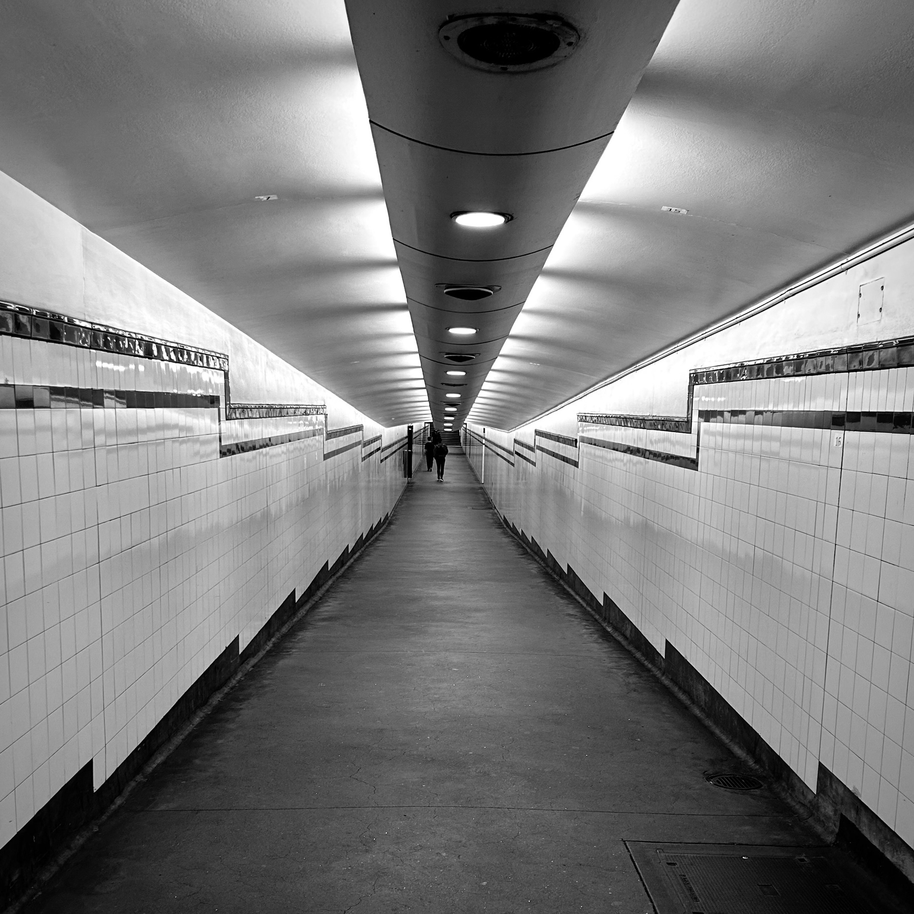 Grayscale photo of an underground pedestrian tunnel