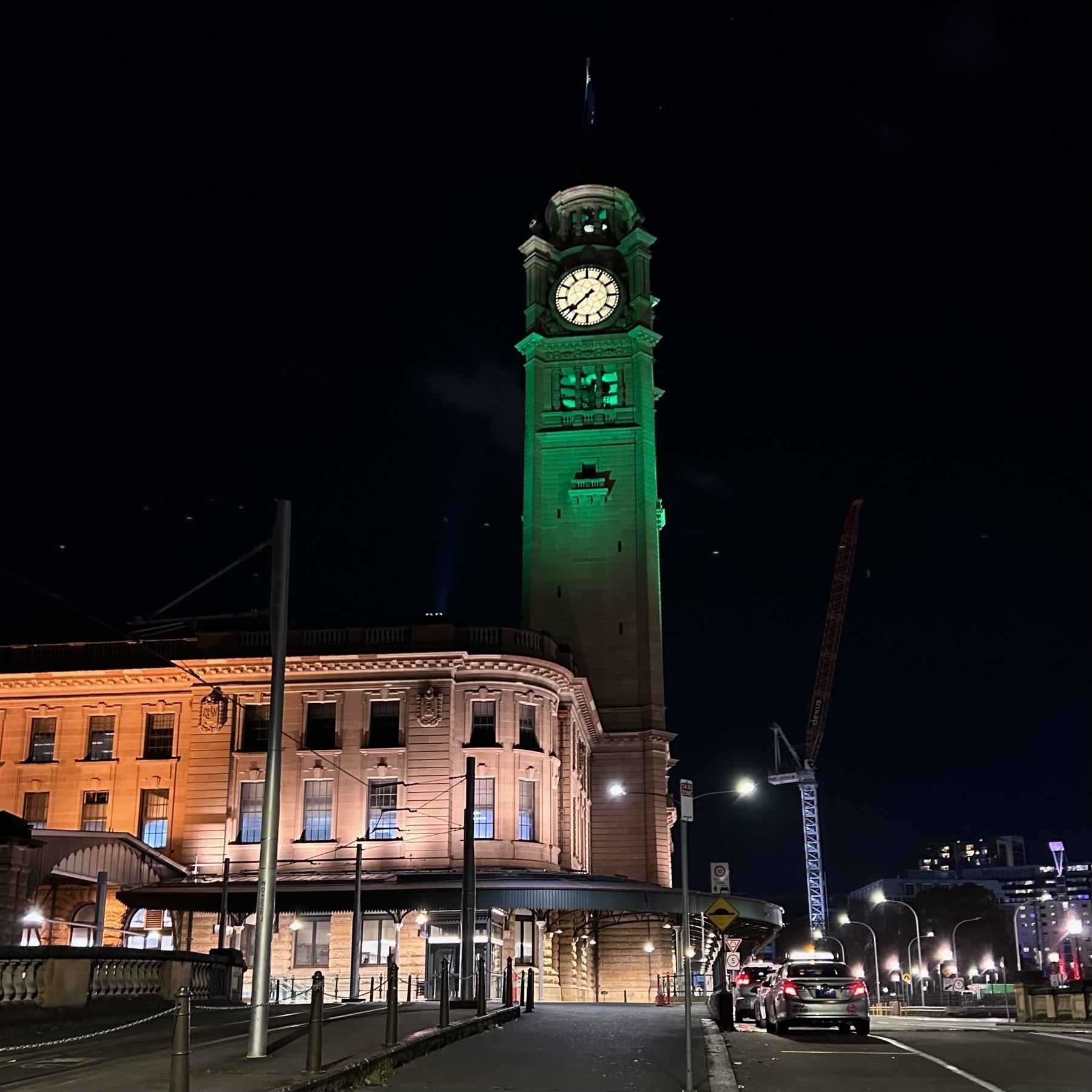 The clocktower above Central Station in Sydney, lit up green at night.