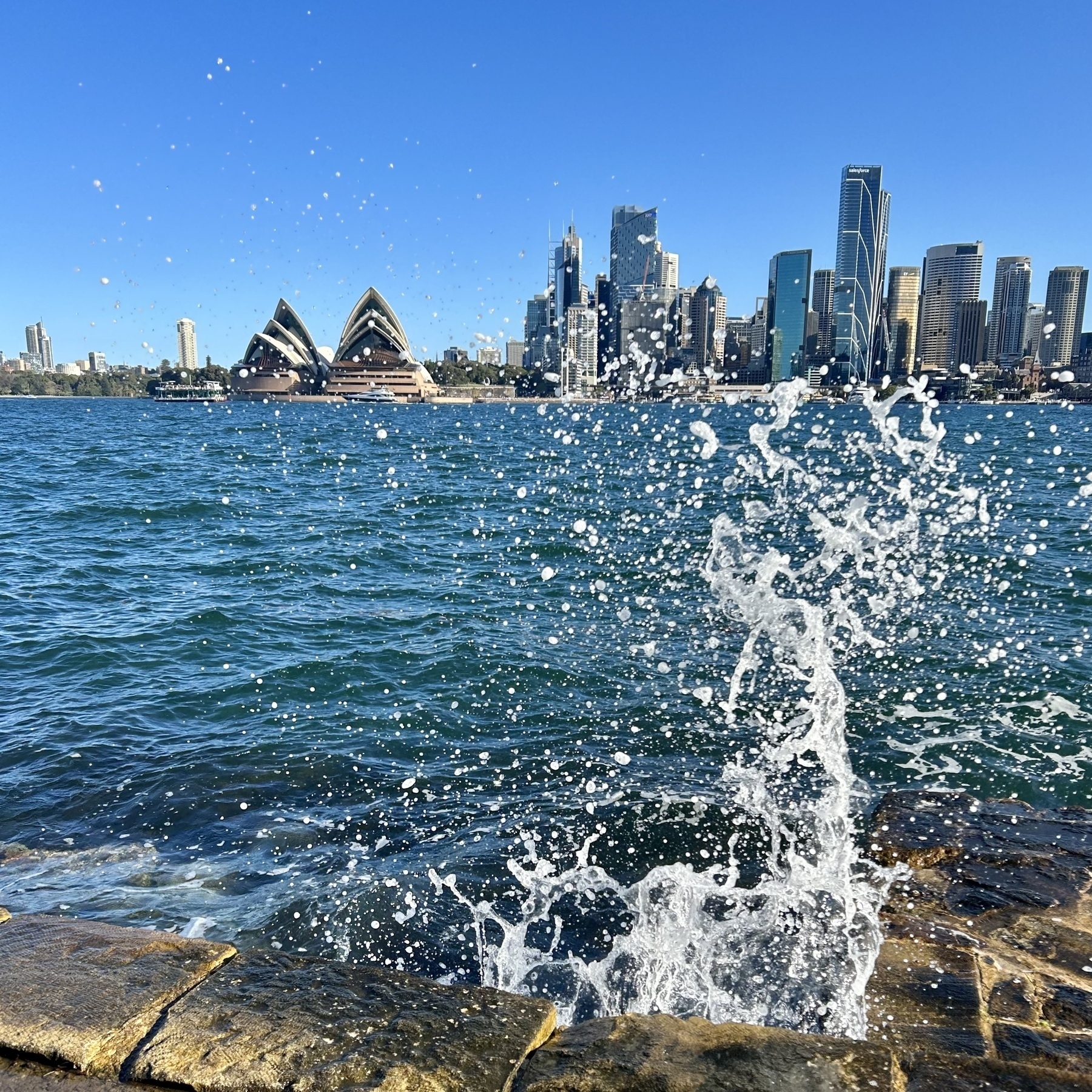 Sydney Opera House with water splashing up in the foreground. 