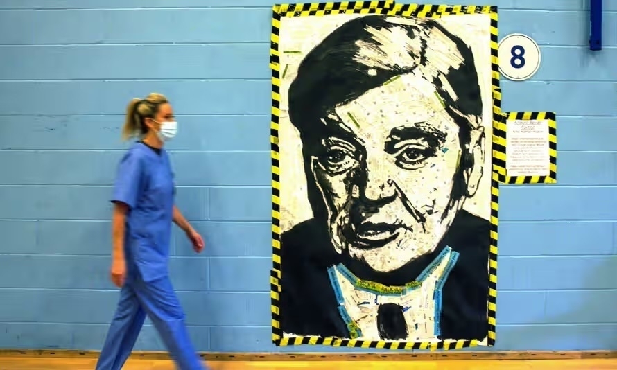 A nurse walks past a portrait of Aneurin Bevan, the architect of the NHS, in Cwmbran, Wales