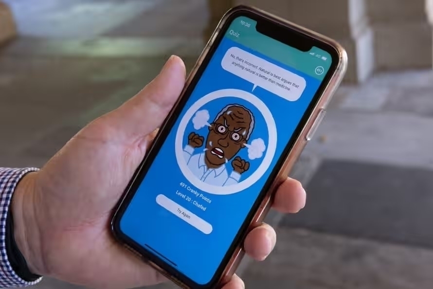 A photograph of a hand holding a phone. The screen displays a version of the Cranky Uncle game used in east Africa. Photograph: Nadir Kinani/The Guardian