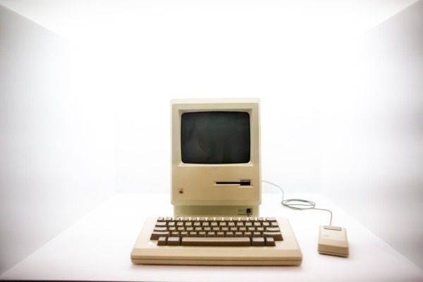 A beige Macintosh computer with a keyboard and mouse, with a bright white background.