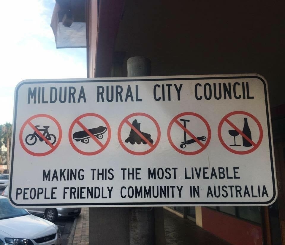 A street sign tyhat says "Mildura Rural City Council: Making this the most liveable, people friendly community in Australia". Underneath are a series of icon sayimng these are not allowed: cycling, skateboarding, rollerblading, using scooters, and drinking alcohol.