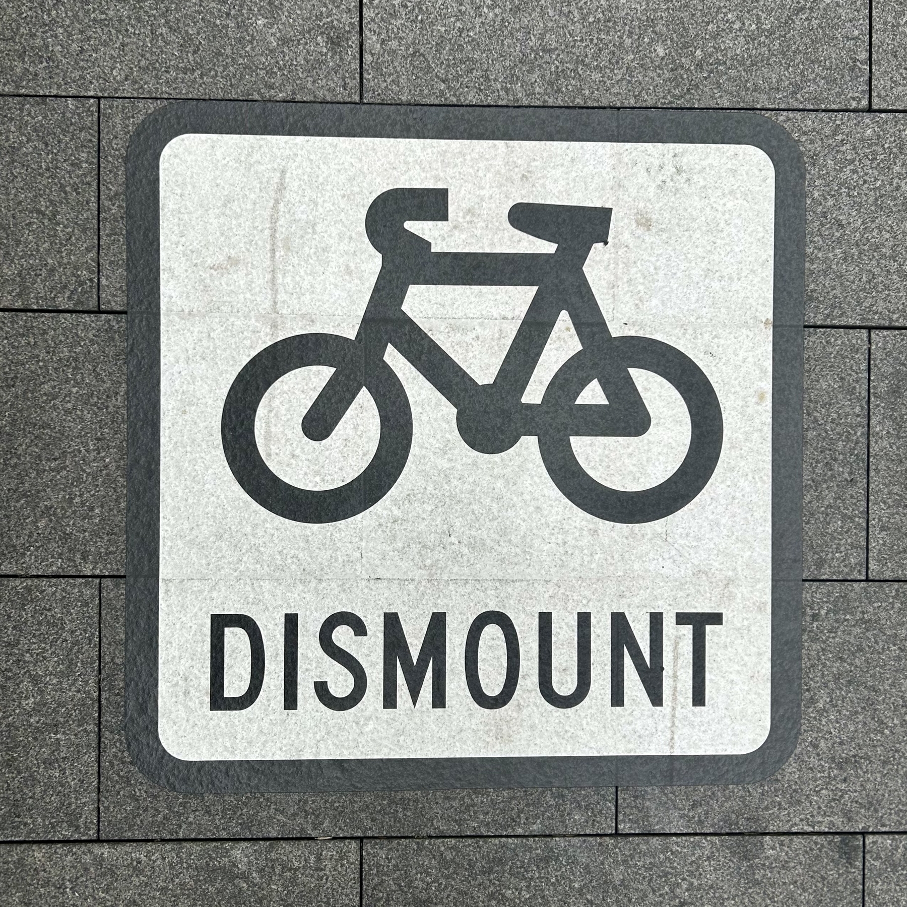 Footpath sign that shows an icon of a bicycle with the word "DISMOUNT"